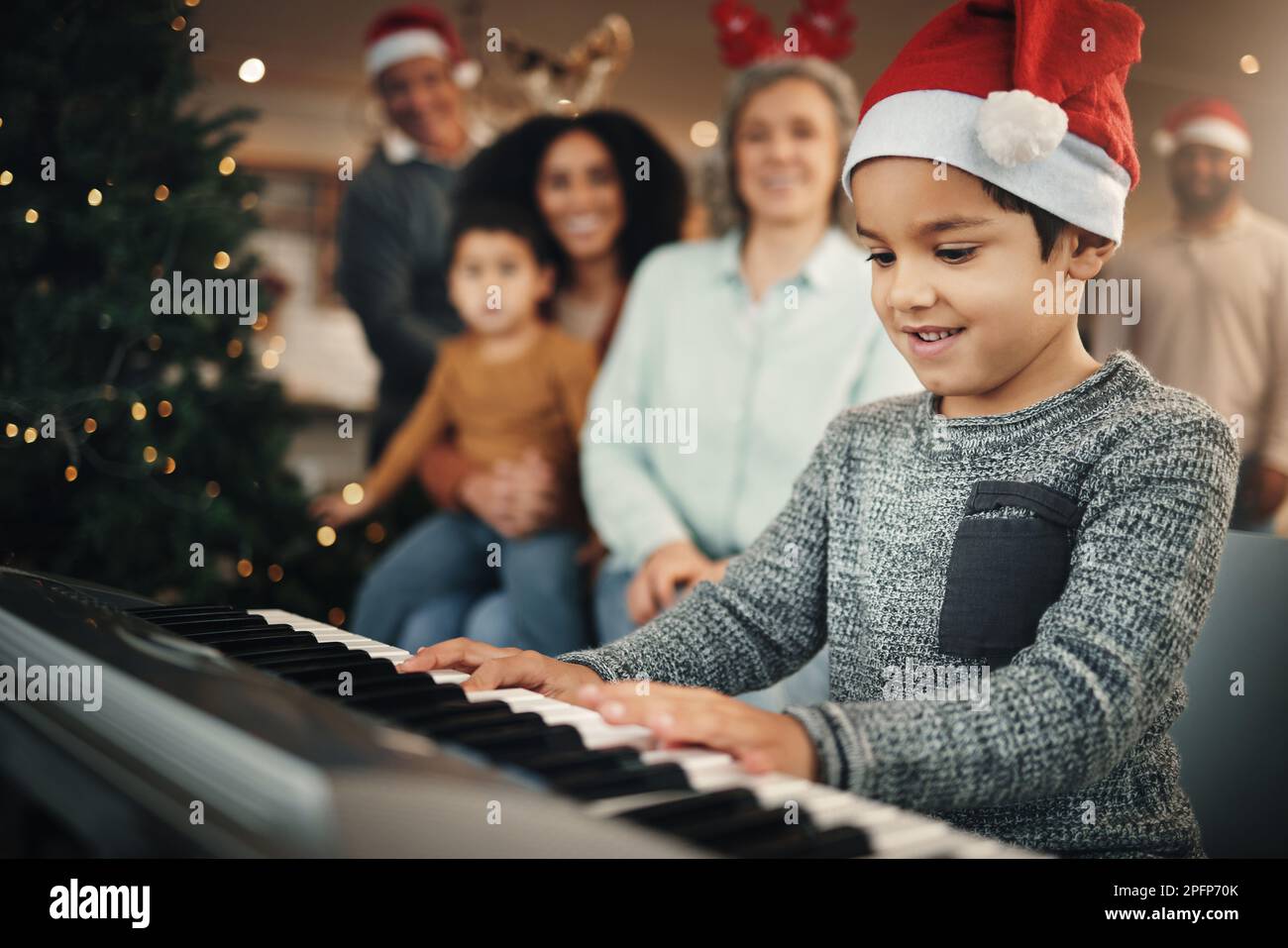 Garçon enfant, clavier musical et noël dans la maison de famille avec le sourire, jouer et créatif avec bonheur. Enfant, jeune musicien et parents de piano pour Banque D'Images