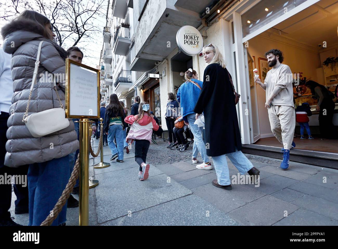 Berlin, Allemagne. 18th mars 2023. Un client sort du glacier « Hokey Pokey » de Prenzlauer Berg avec un cône de glace. Le soleil brille et la température est d'environ 18 degrés Celsius. Credit: Carsten Koall/dpa/Alay Live News Banque D'Images