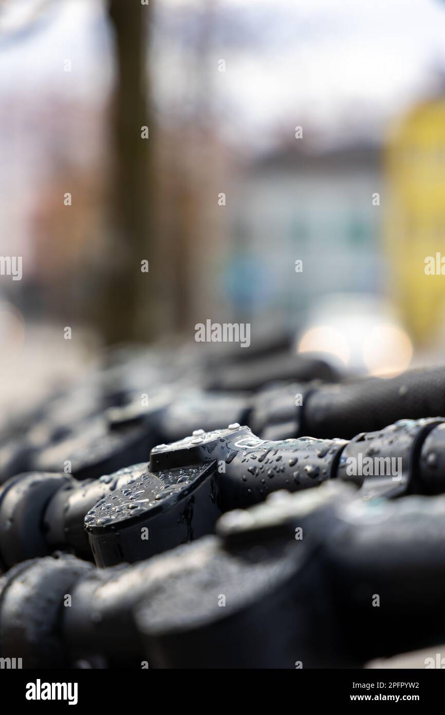 Barres de poignée humides des scooters électriques. Scooters électriques debout sous la pluie dans la rue. Banque D'Images