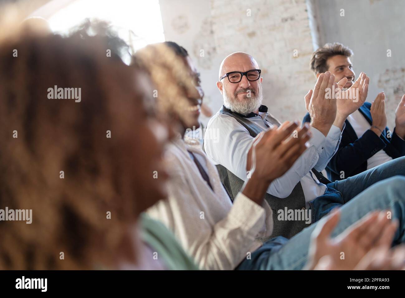 Un groupe de professionnels vêtus d'une tenue de travail décontractée applaudir et sourire lors d'une conférence ou d'une réunion d'affaires dans un bureau lumineux - se concentrer sur un milieu de travail Banque D'Images