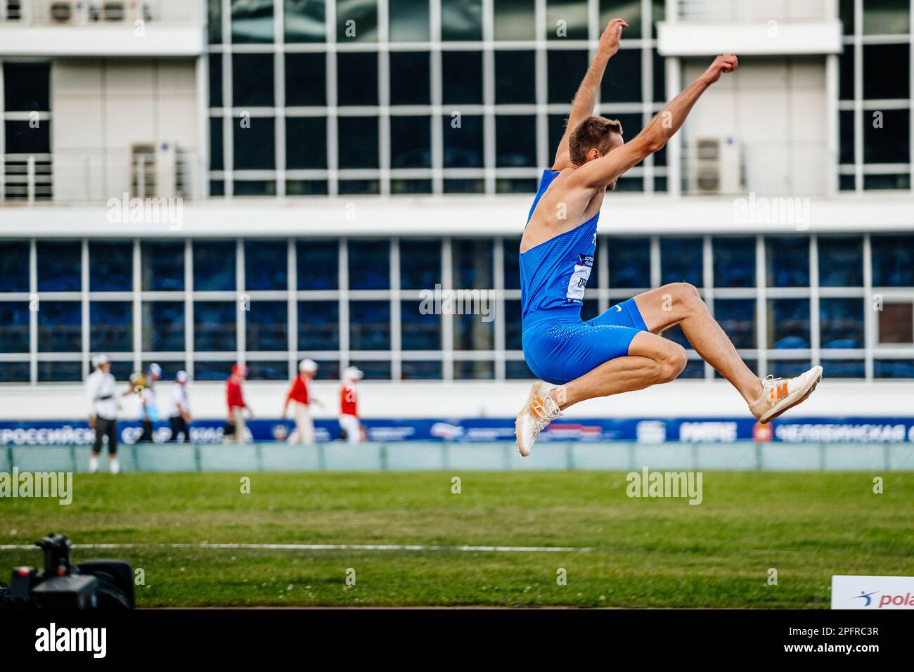 Athlète masculin saut long dans l'athlétisme de compétition, chaussures à pointes pour sauter Adidas et collants Nike, photo de sport Banque D'Images