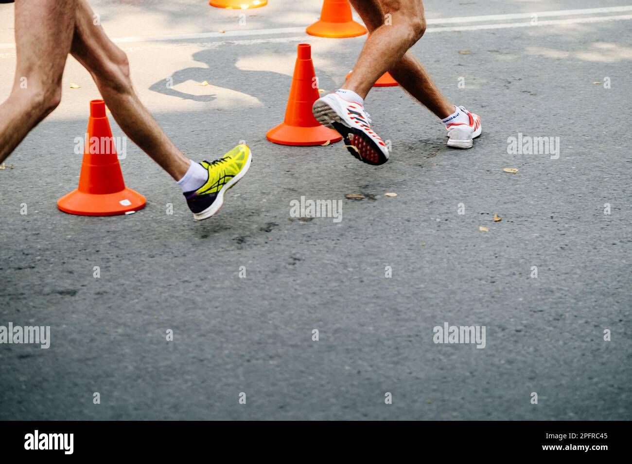 Jambes athlète masculin en compétition de course, chaussures de sport pour la marche Adidas et Asics Banque D'Images