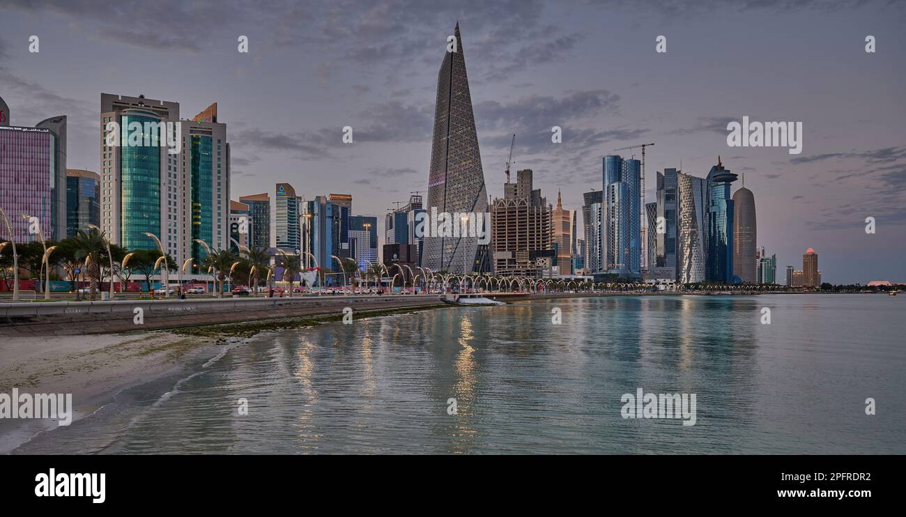 Doha Qatar Skyline de la promenade corniche au coucher du soleil montrant les gratte-ciel de West Bay lumières reflétées dans le golfe arabe Banque D'Images