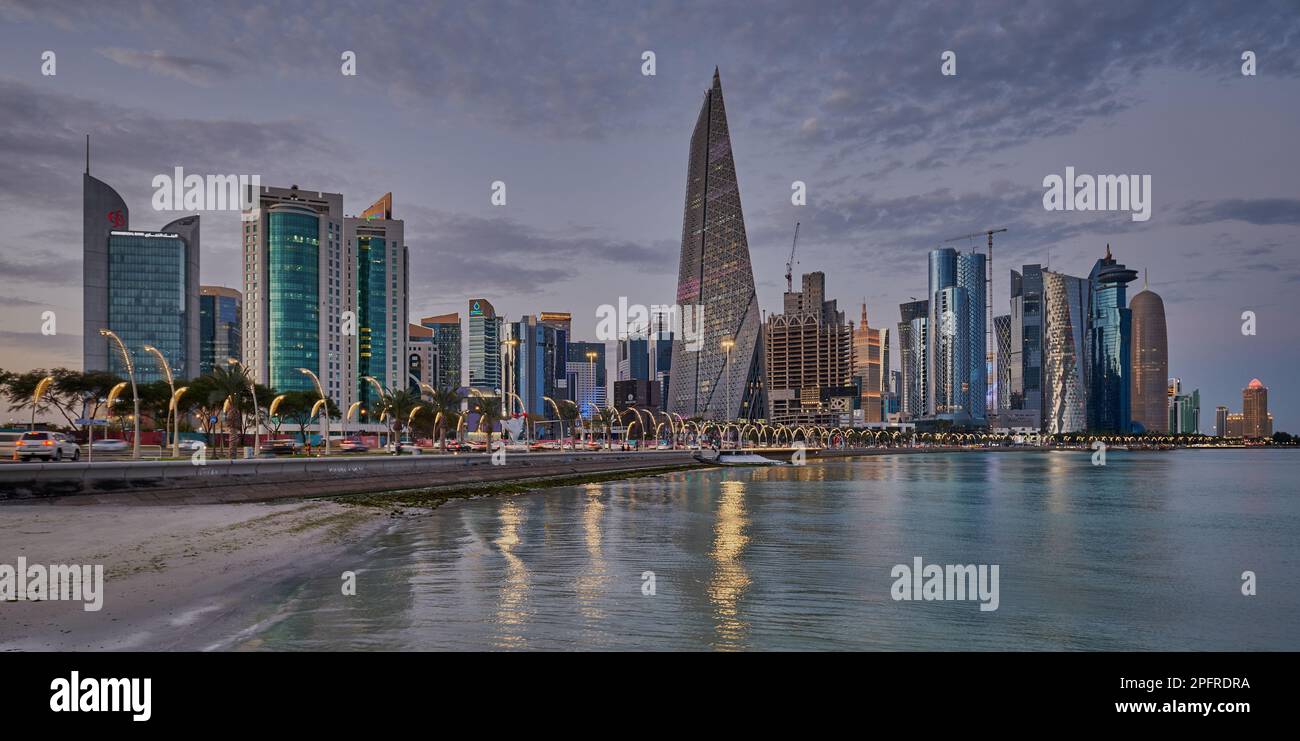 Doha Qatar Skyline de la promenade corniche au coucher du soleil montrant les gratte-ciel de West Bay lumières reflétées dans le golfe arabe Banque D'Images