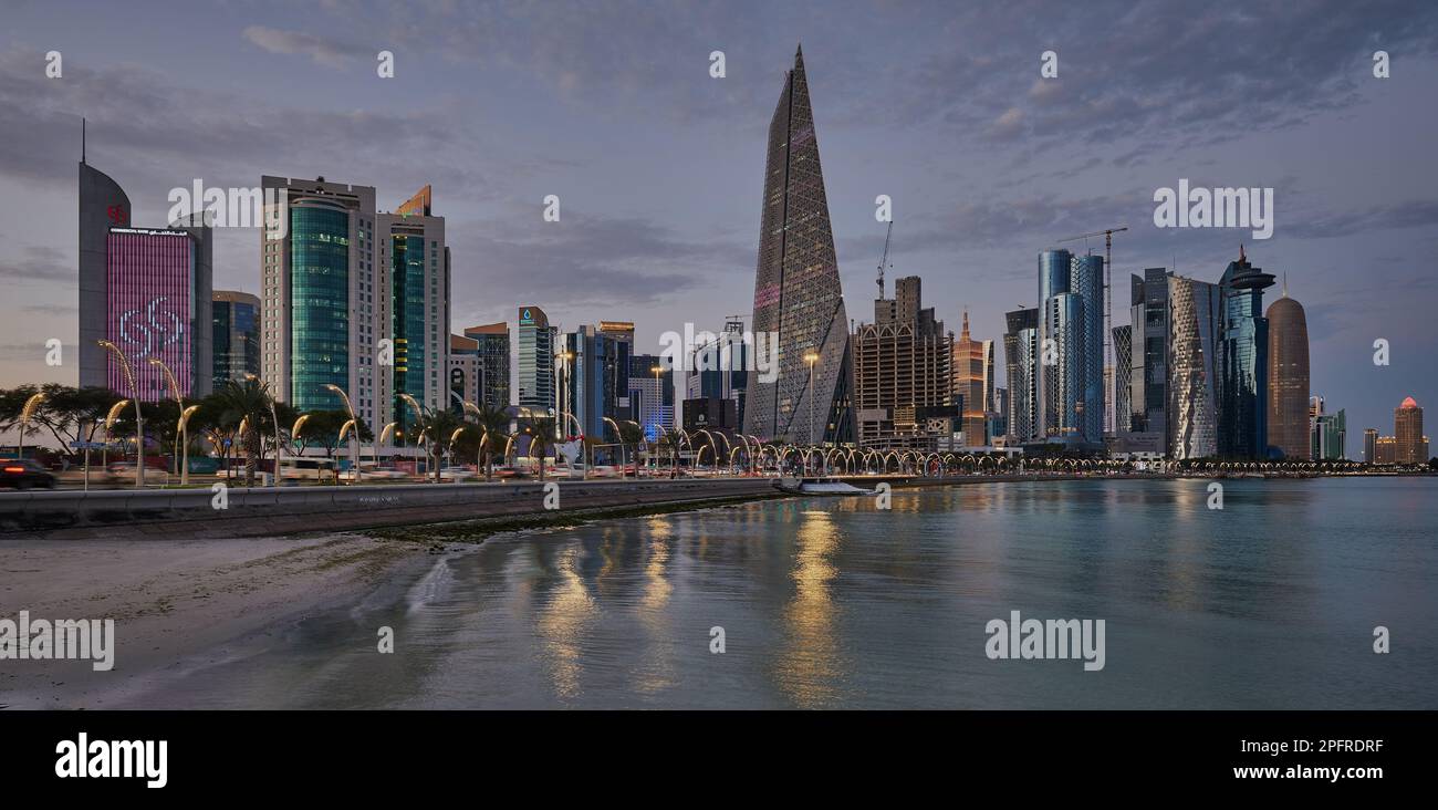 Doha Qatar Skyline de la promenade de corniche au crépuscule montrant les gratte-ciel de West Bay lumières reflétées dans le golfe arabe Banque D'Images