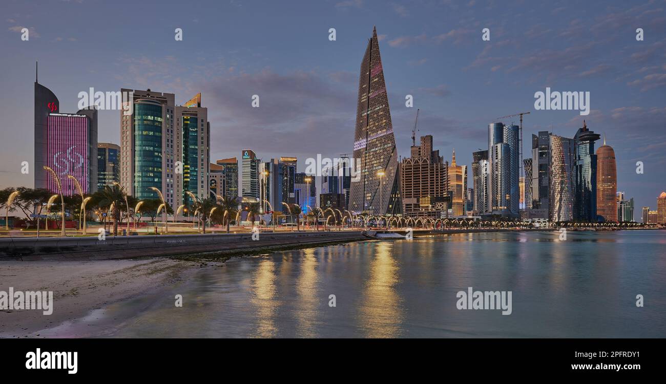 Doha Qatar Skyline de la promenade de corniche au crépuscule montrant les gratte-ciel de West Bay lumières reflétées dans le golfe arabe Banque D'Images