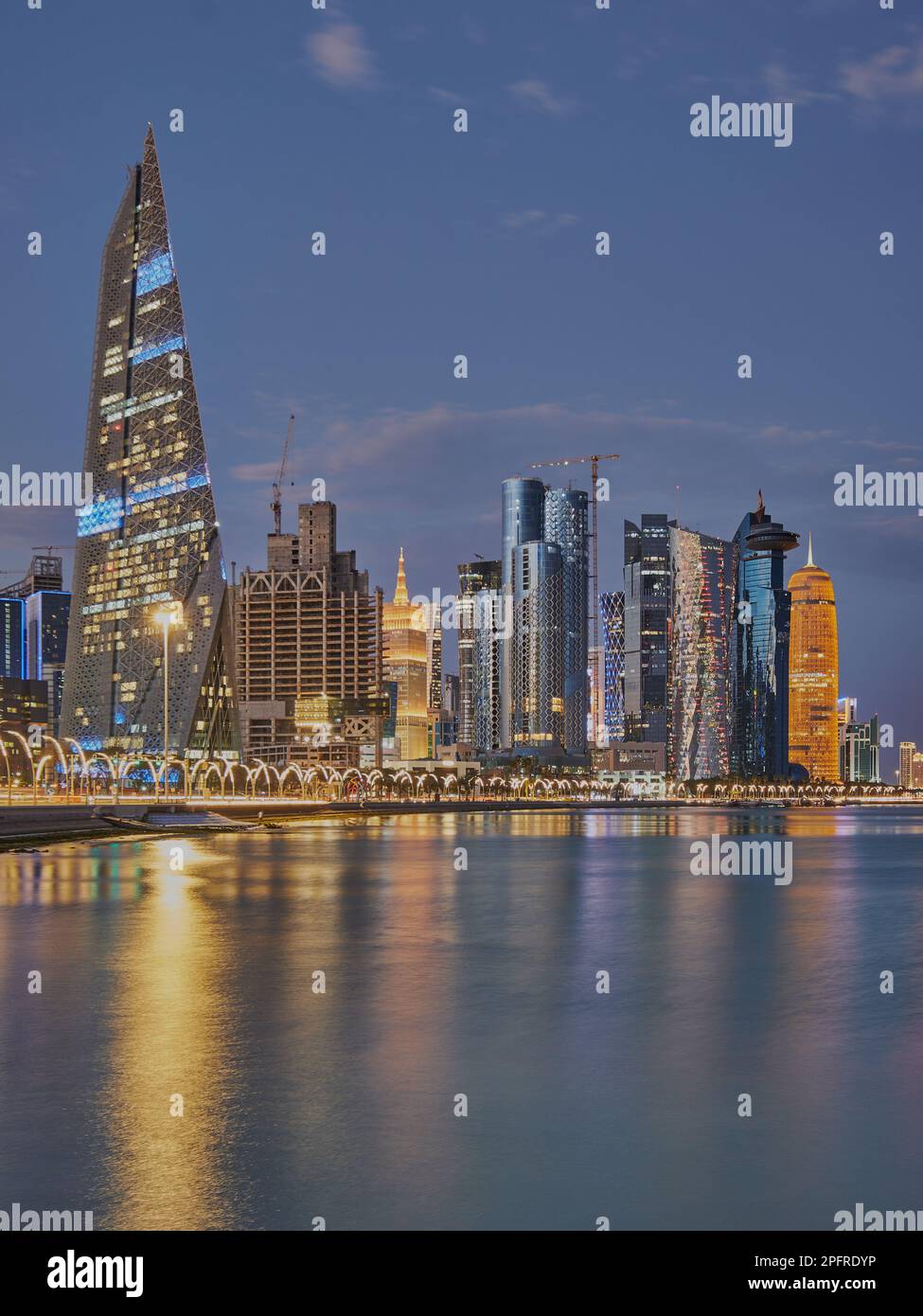 Doha Qatar Skyline de la promenade de corniche au crépuscule montrant les gratte-ciel de West Bay lumières reflétées dans le golfe arabe Banque D'Images