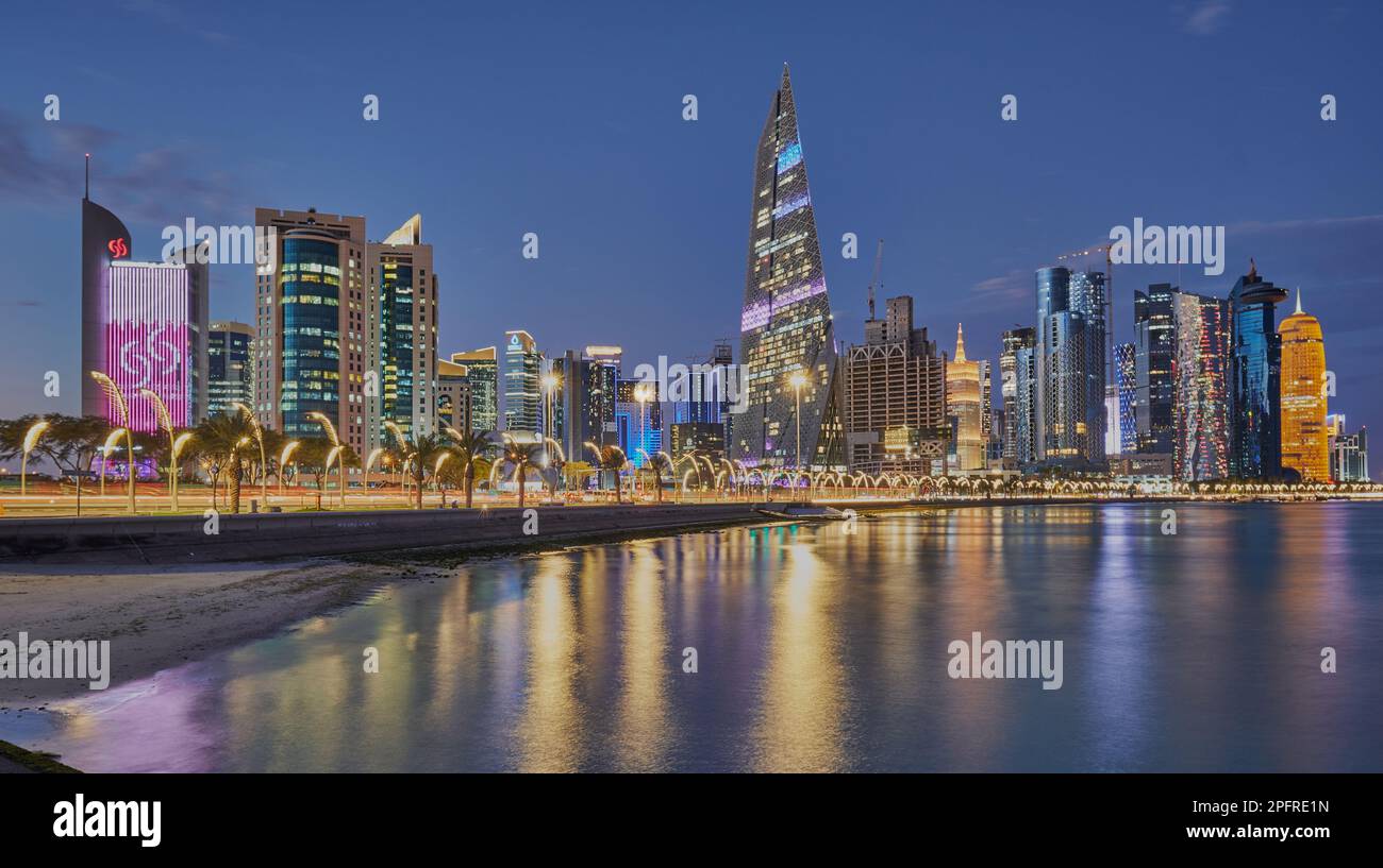 Doha Qatar Skyline de la promenade de corniche au crépuscule montrant les gratte-ciel de West Bay lumières reflétées dans le golfe arabe Banque D'Images