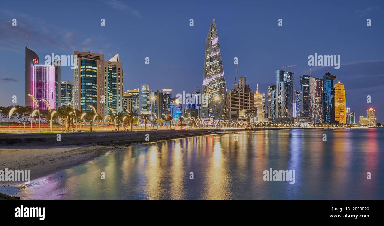 Doha Qatar Skyline de la promenade de corniche au crépuscule montrant les gratte-ciel de West Bay lumières reflétées dans le golfe arabe Banque D'Images