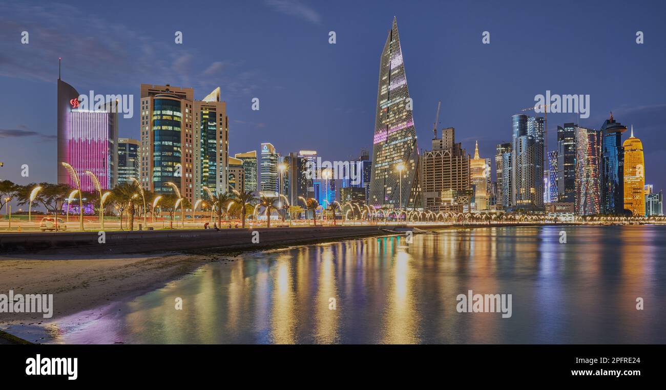 Doha Qatar Skyline de la promenade de corniche au crépuscule montrant les gratte-ciel de West Bay lumières reflétées dans le golfe arabe Banque D'Images