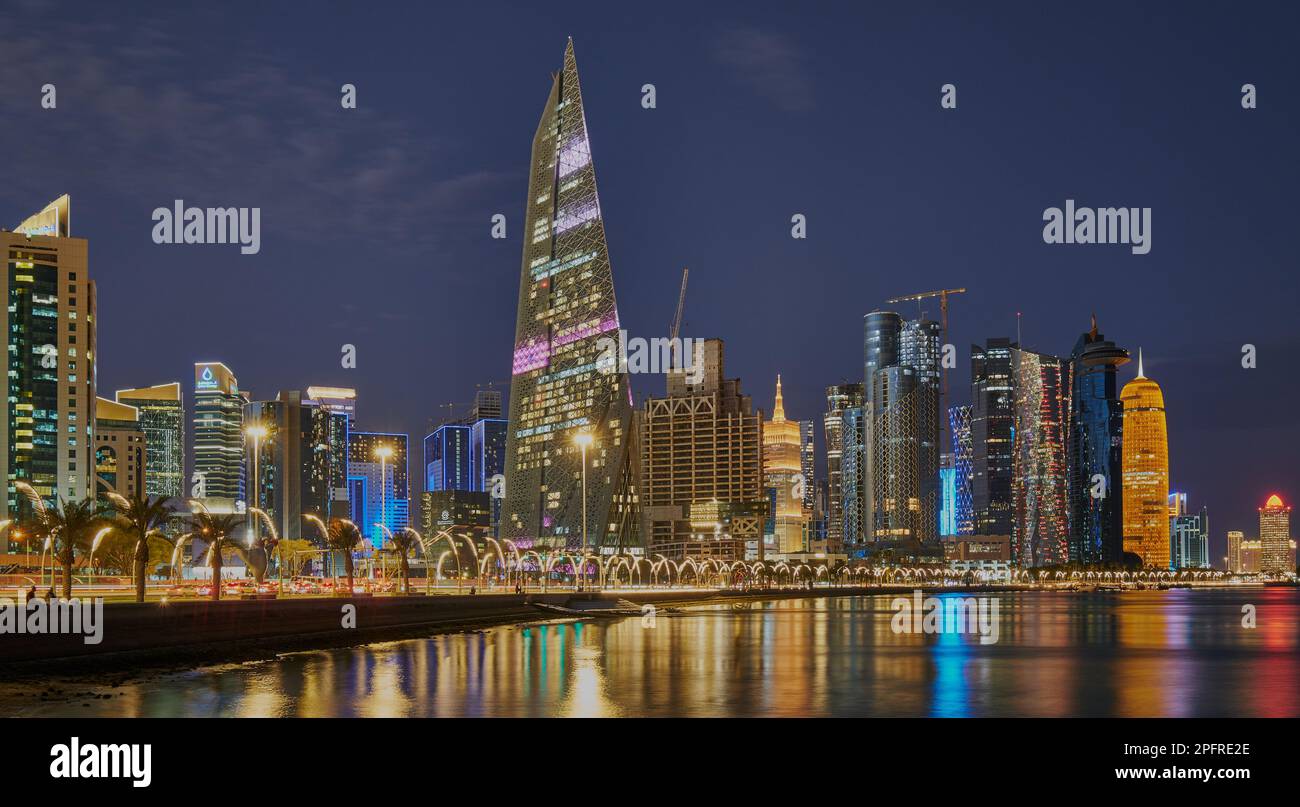 Doha Qatar Skyline de la promenade de corniche au crépuscule montrant les gratte-ciel de West Bay lumières reflétées dans le golfe arabe Banque D'Images