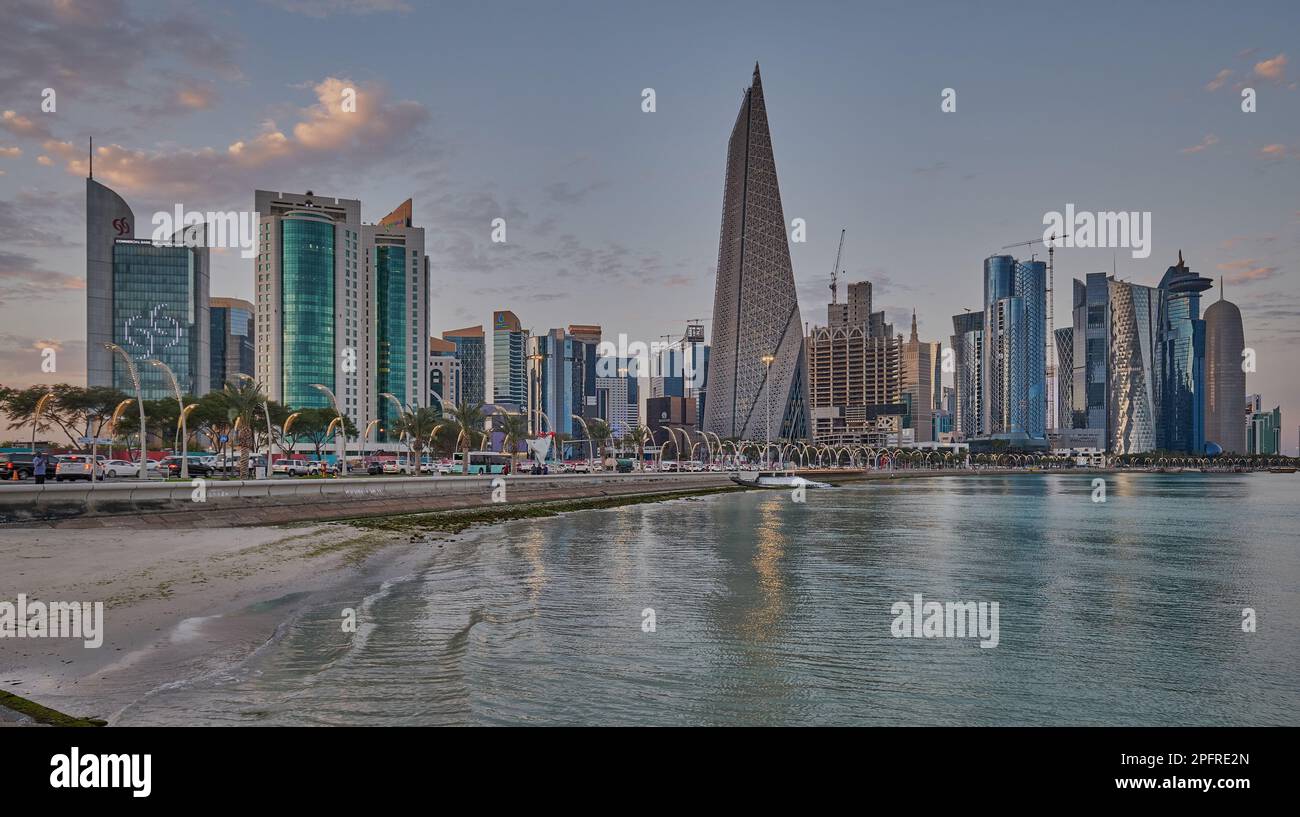 Doha Qatar Skyline de la promenade corniche au coucher du soleil montrant les gratte-ciel de West Bay lumières reflétées dans le golfe arabe Banque D'Images