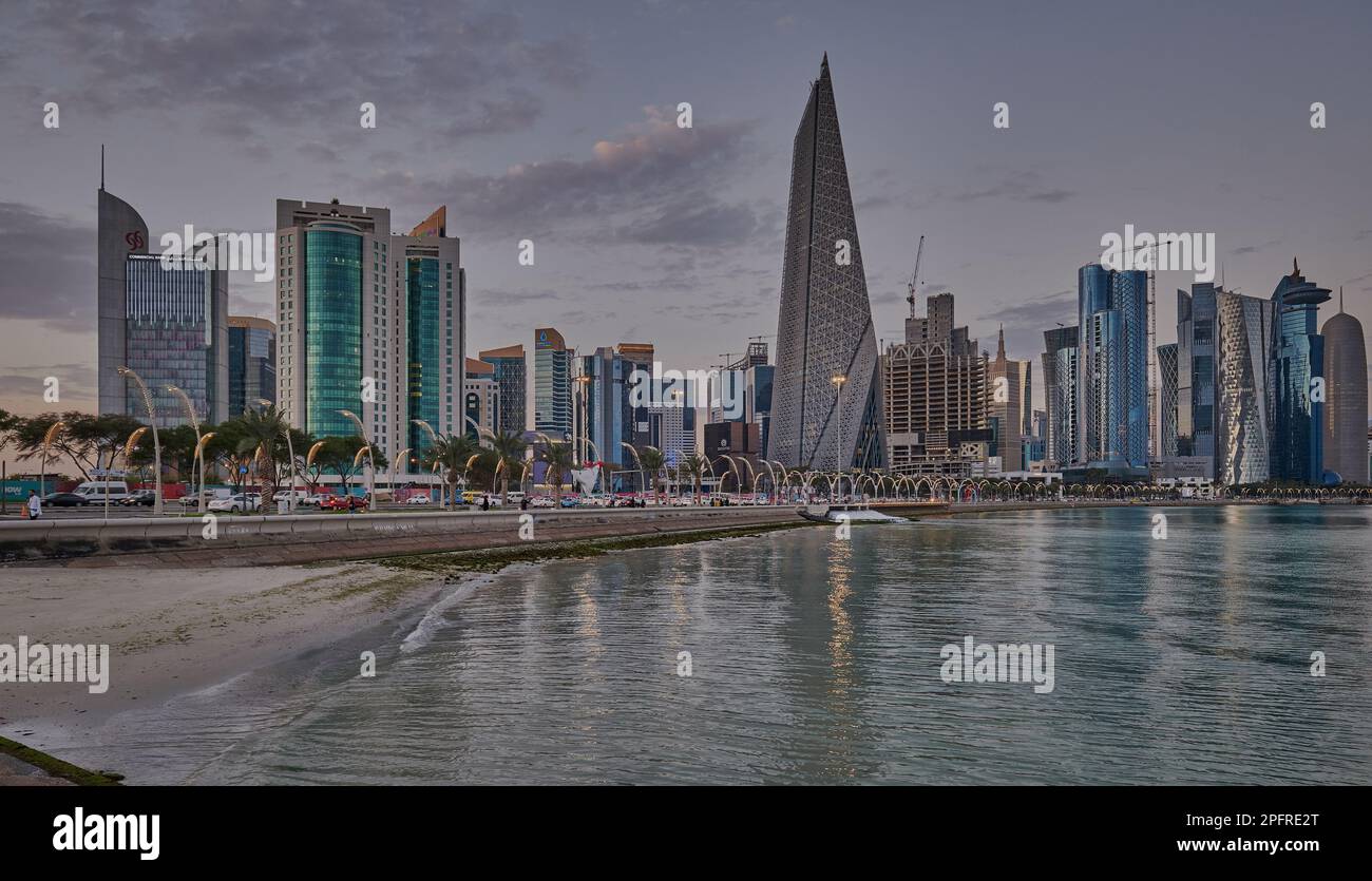 Doha Qatar Skyline de la promenade corniche au coucher du soleil montrant les gratte-ciel de West Bay lumières reflétées dans le golfe arabe Banque D'Images
