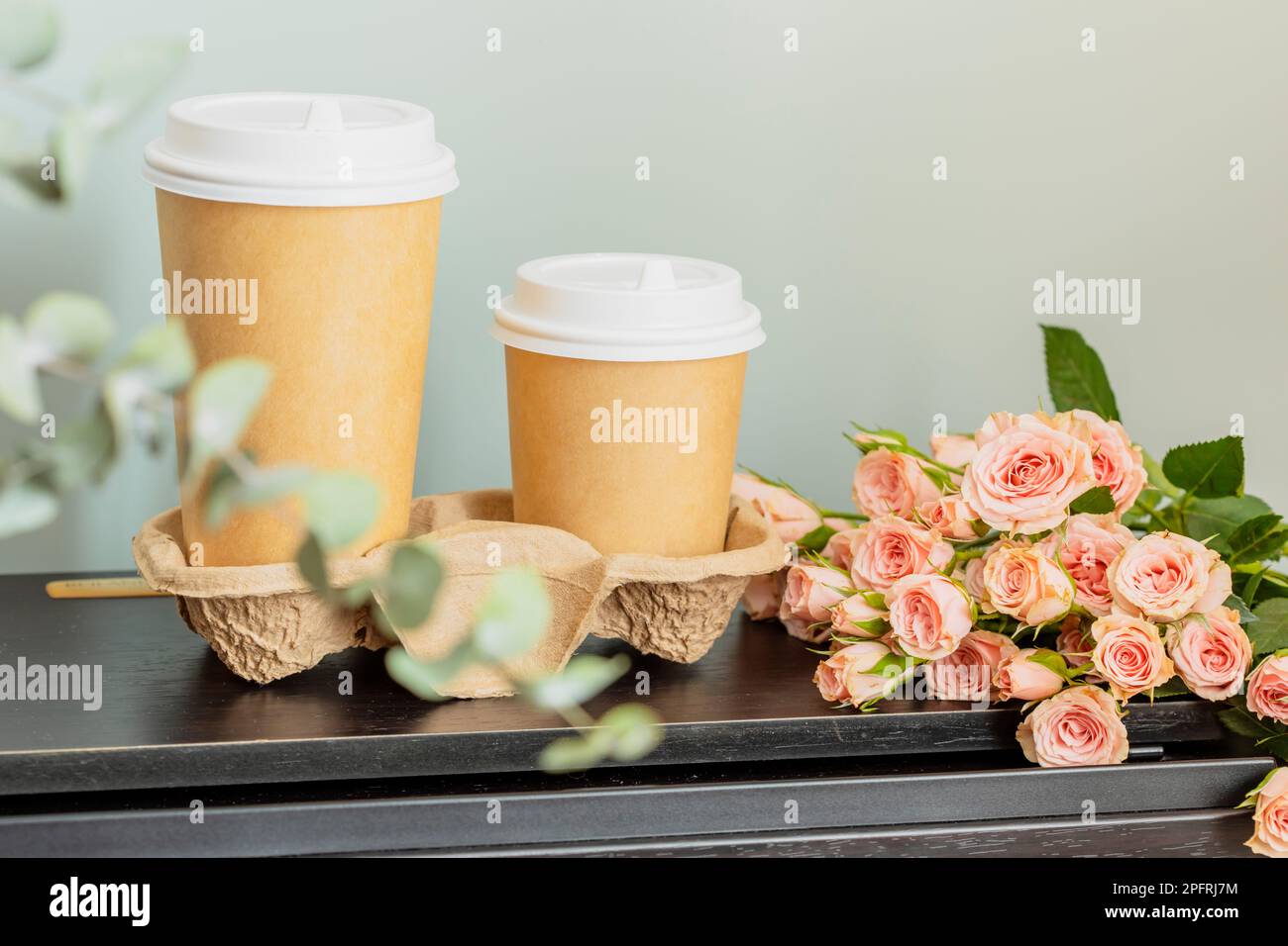 Printemps romantique composition de vacances avec deux tasses jetables de café et bouquet de roses sur table en bois. Concept de rencontres ou d'amour. café à emporter. Mot Banque D'Images