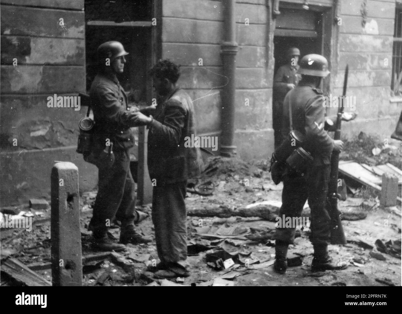 En janvier 1943, les nazis sont arrivés pour arrondir les Juifs du ghetto de Varsovie les Juifs, résolus au combattre, ont pris la SS avec des armes maison et primitives. Les défenseurs ont été exécutés ou déportés et la zone du ghetto a été systématiquement démolie. Cet événement est connu sous le nom de soulèvement du ghetto. Cette image montre un combattant de la résistance juive fouillé par un soldat. Cette image est tirée du dossier photographique allemand de l'événement, connu sous le nom de rapport Stroop. Banque D'Images