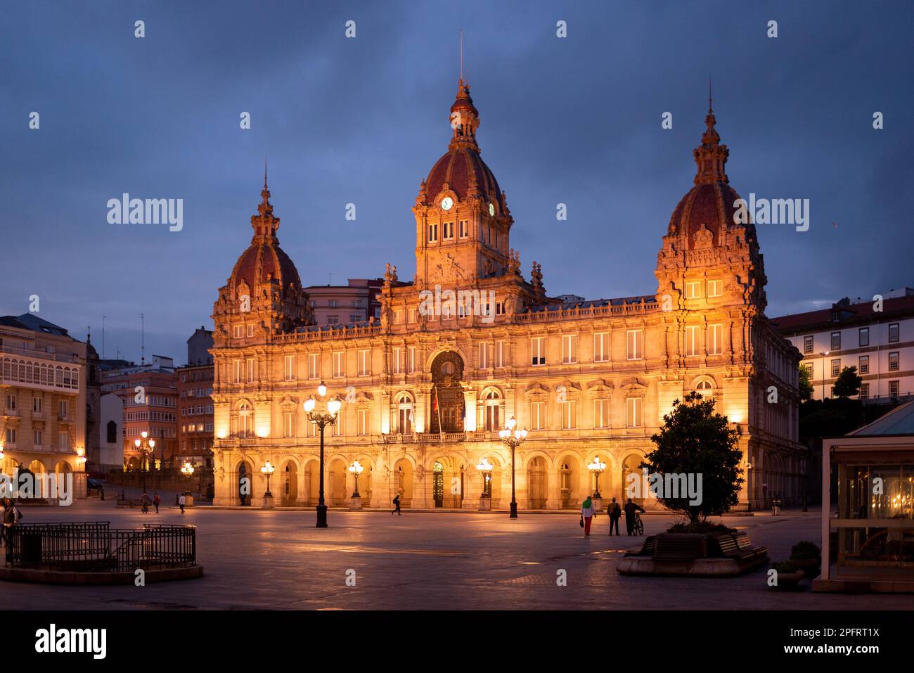 La nuit tombe, la Plaza Maria Pita à la Coruña, Galice, Espagne, se transforme en un pays merveilleux magique avec ses bâtiments éclairés et ses fontaines c. Banque D'Images
