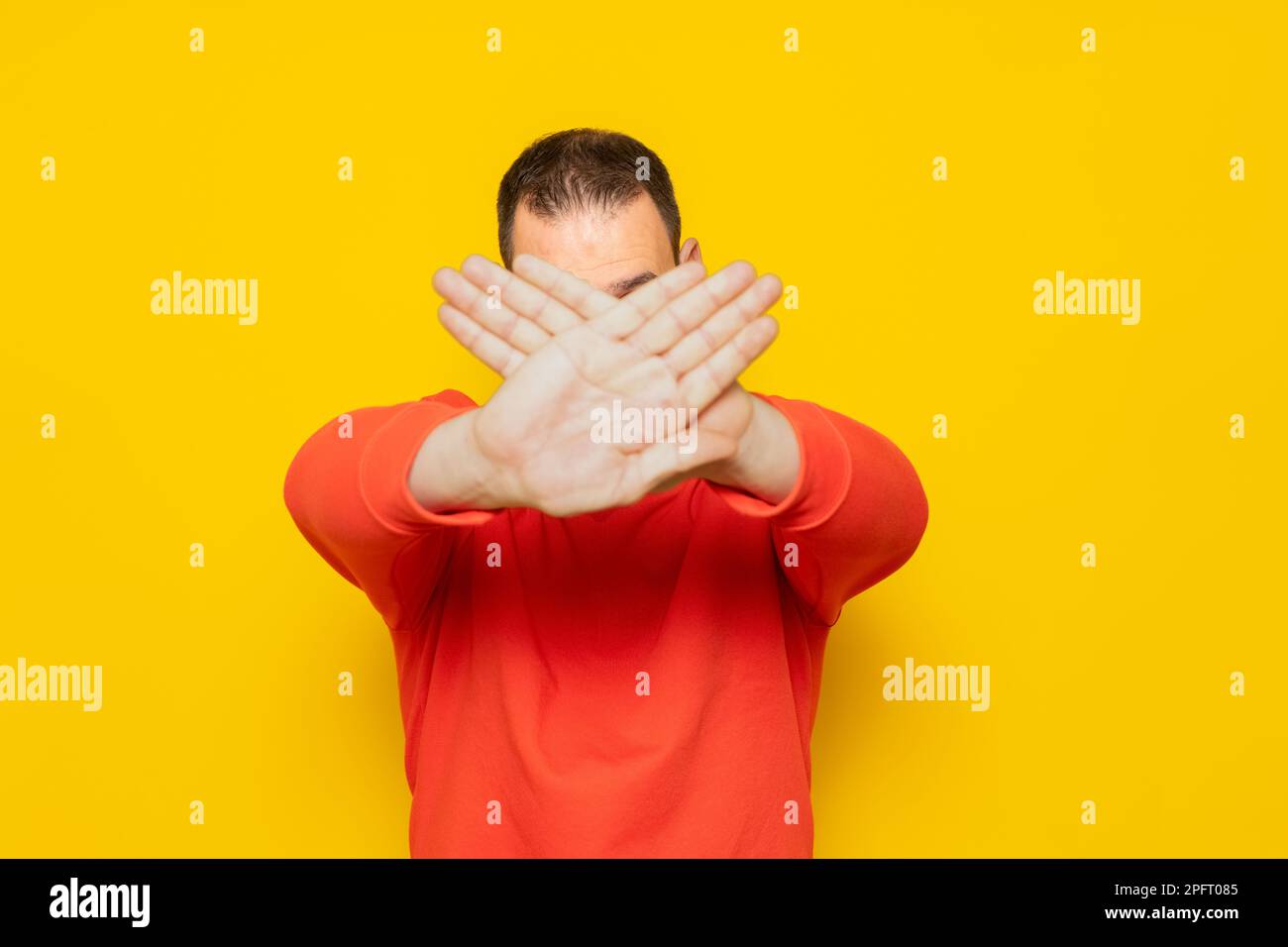 Hispanique homme debout sur fond jaune expression de rejet croisant ses bras et les paumes couvrant son visage faisant un signe négatif. Banque D'Images