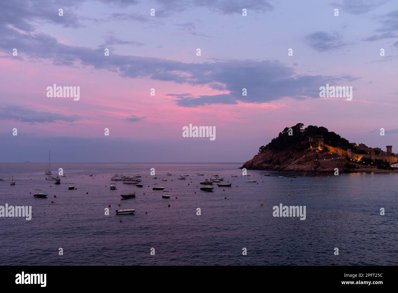 Le ciel devient rose et orange lorsque le soleil se couche sur Tossa de Mar, en Espagne, créant une vue pittoresque depuis la plage et le château Banque D'Images