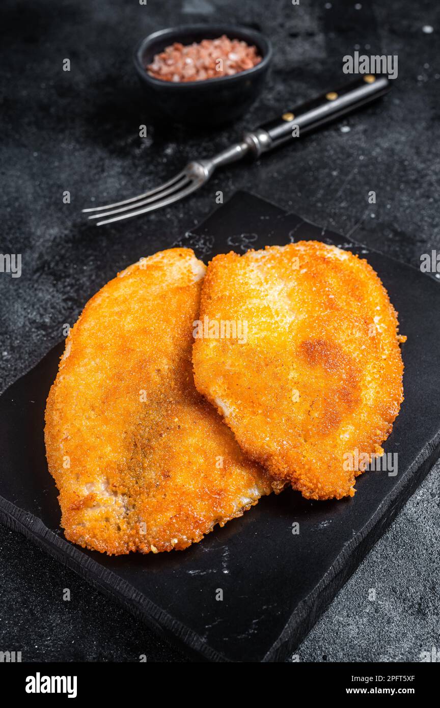 Filets de tilapia panés frits sur un plateau en marbre. Arrière-plan noir. Vue de dessus. Banque D'Images