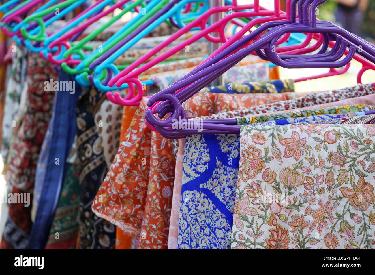 Porte manteau avec un motif floral de sélection sur les cintres des vêtements colorés Banque D'Images