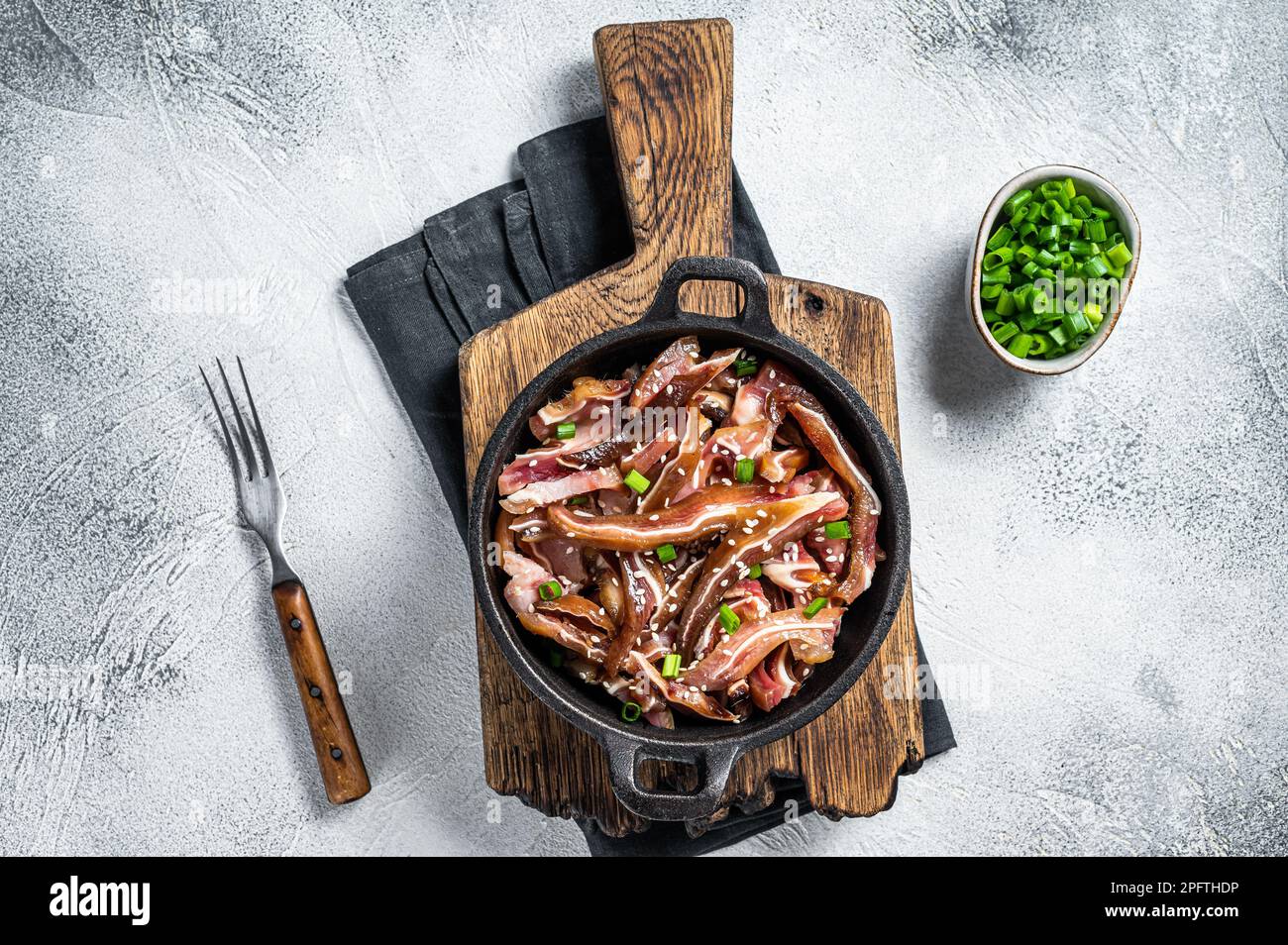 Oreilles de porc épicées frites servies dans une poêle. arrière-plan blanc. Vue de dessus. Banque D'Images