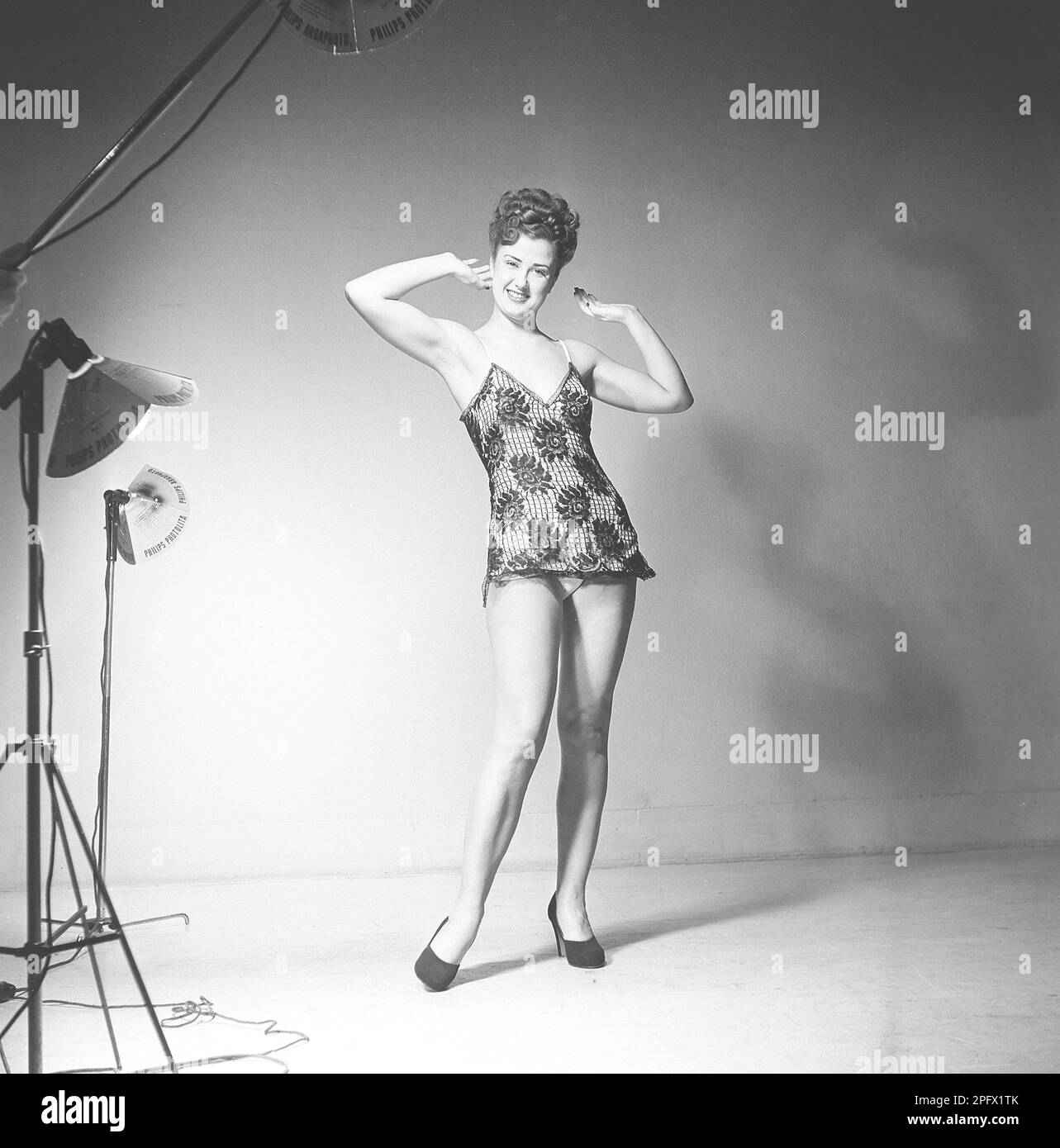 Suède 1948. Kristoffersson Ref AT46-9 Femme en studio photo de retour dans la journée. Une jeune femme aux jambes longues et élancées, debout dans une robe courte pose et sourit à la caméra. Elle a ses cheveux fait dans le manoir typique de 1940s et sur ses pieds elle a des chaussures noires à talons hauts. Suède 1948. Kristoffersson réf. AT46-10 Banque D'Images