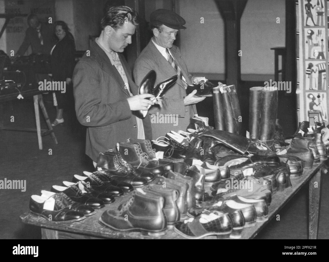 Shopping dans le 1940s. Deux hommes à une table avec des chaussures pour hommes regardant chaque paire. Suède 1946 Banque D'Images