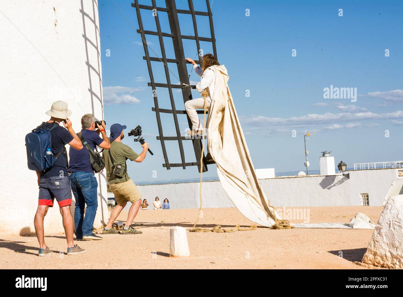 Campo de Criptana, Espagne - 22 juin 2022: Moulin à vent avec l'homme grimpant sur les lames pour installer le tissu pour le faire fonctionner et les photographes et la vidéo ma Banque D'Images