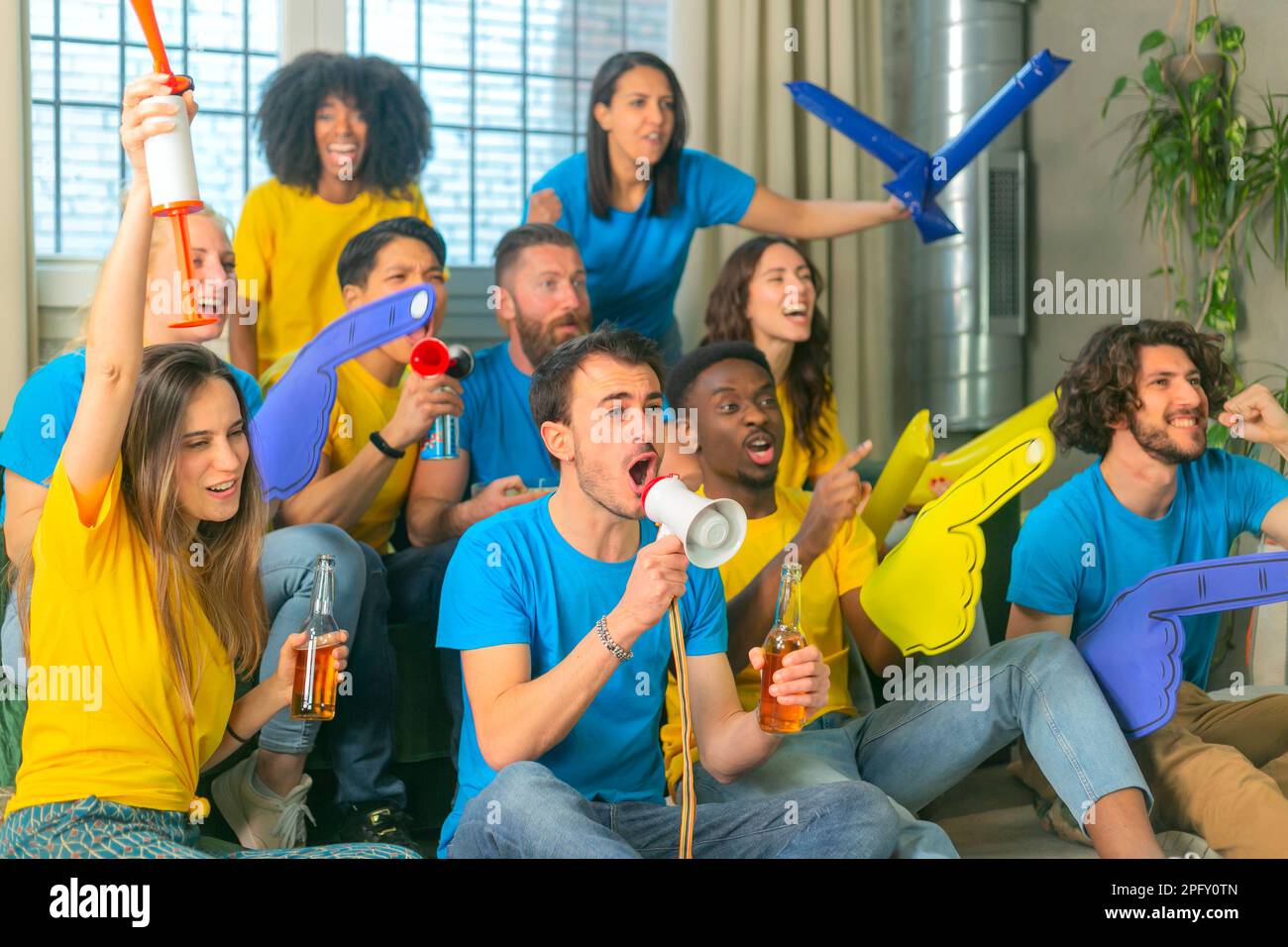 Groupe multiethnique d'amis regardant et soutenant le match de football à la maison. Banque D'Images