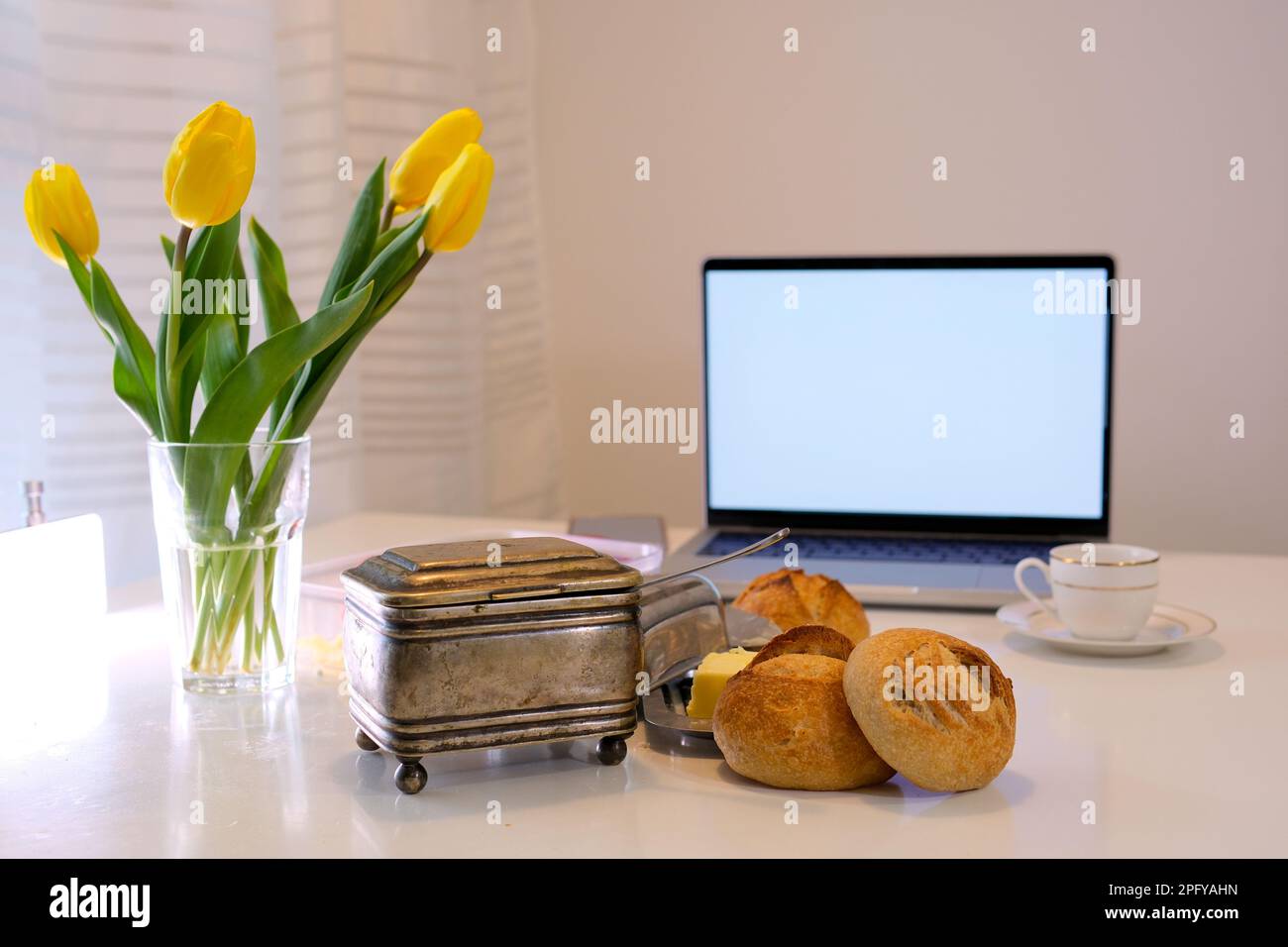 ordinateur portable fond blanc sur l'écran lieu pour le texte publicitaire demain à la tasse de café délicieux pâtisseries fraîches petits pains vieux rare sucre bol tulipes jaunes près de fenêtre blanche image lumineuse repos détente travail Banque D'Images
