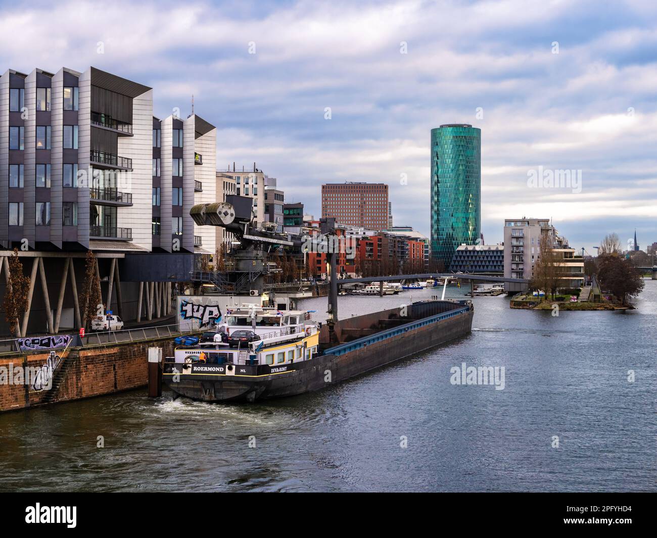 Francfort-sur-le-main, Allemagne - 29 janvier 2023 : navire industriel devant la zone habitable de West Harbour à Francfort-sur-le-main, Allemagne, par temps couvert. Banque D'Images