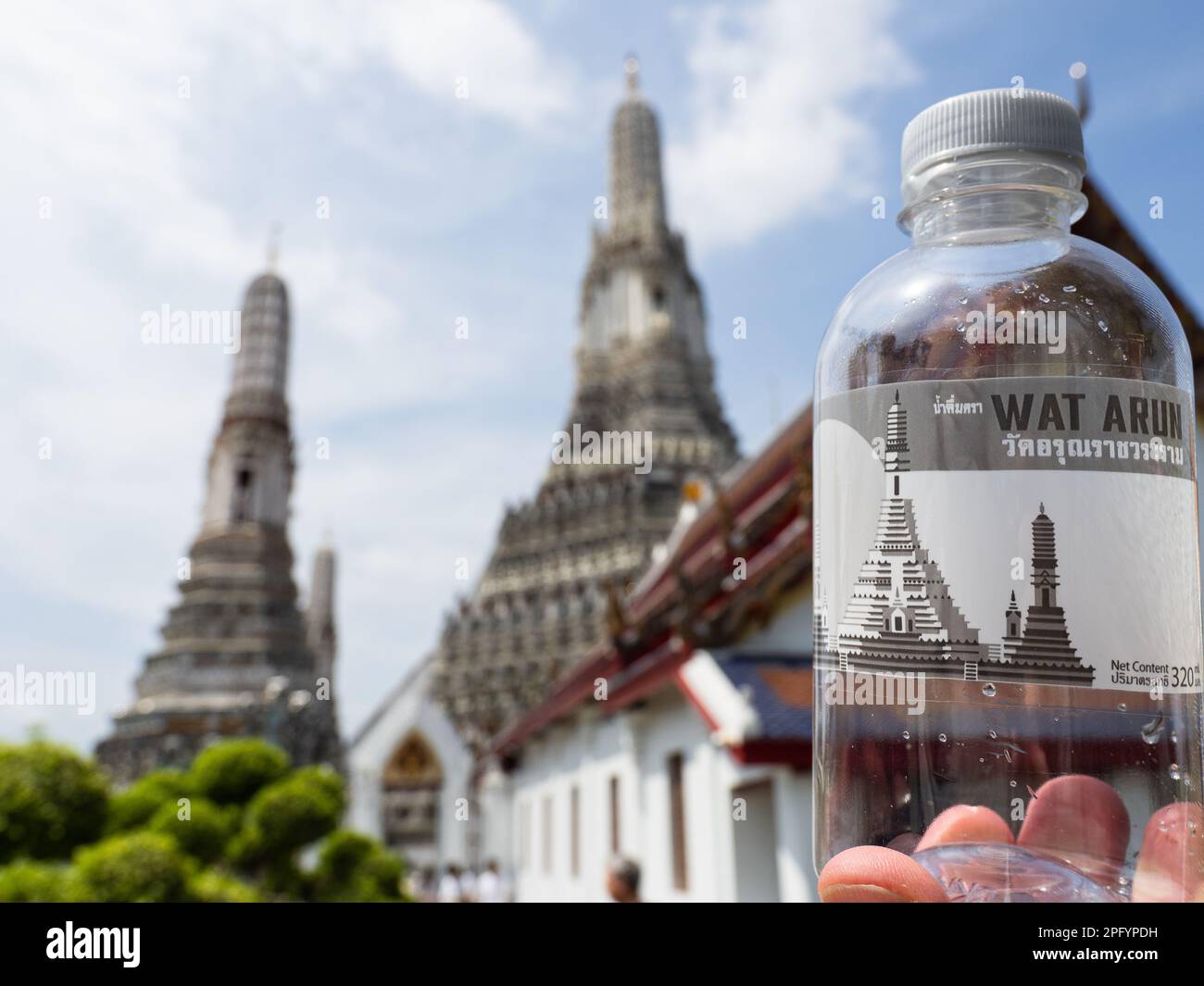 Sur cette photo, une bouteille d'eau avec un autocollant Wat Arun est maintenue contre le temple de Bangkok, en Thaïlande. Wat Arun, également connu sous le nom de Temple de D. Banque D'Images