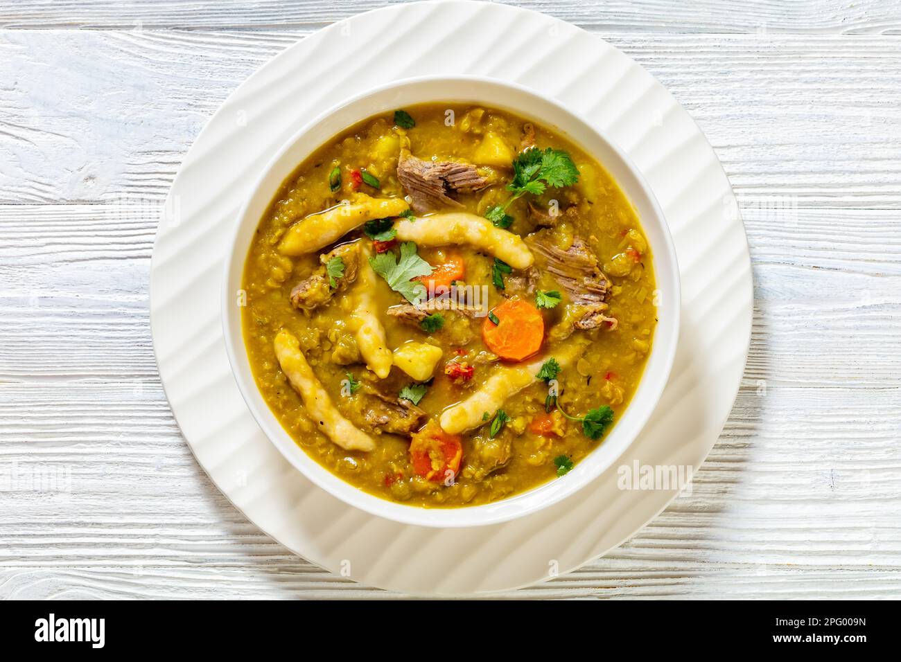 petits pois, soupe de petits pois avec boulettes, légumes et bœuf dans un bol blanc sur table en bois blanc, cuisine jamaïcaine, plat, gros plan Banque D'Images