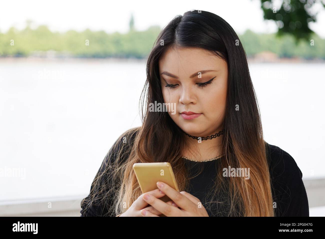 Young Asian woman looking at message texte sur son smartphone Banque D'Images