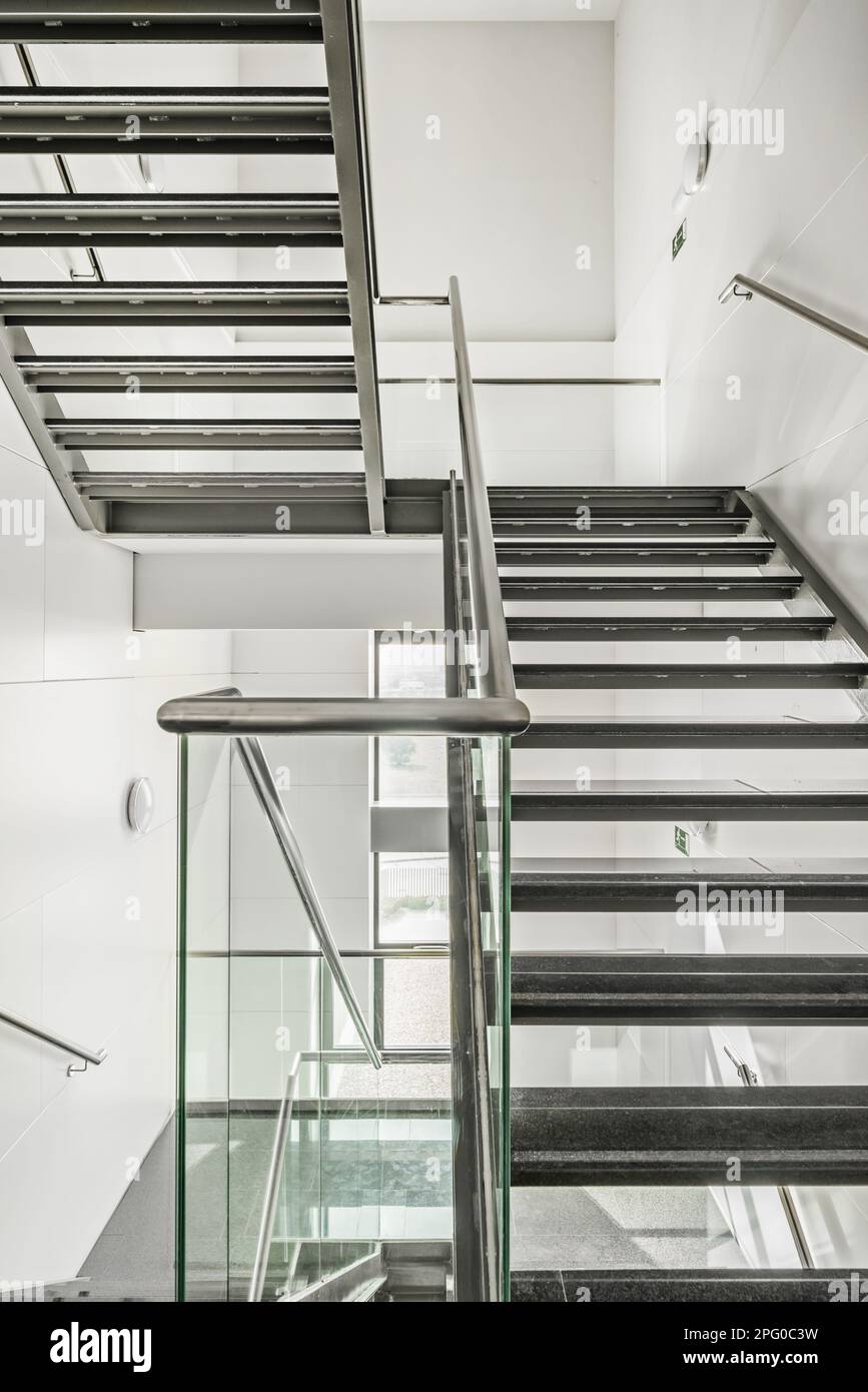 Escaliers légers en acier inoxydable, verre trempé, rails en acier, fenêtres, paliers et marches en granit noir poli dans un bureau b Banque D'Images