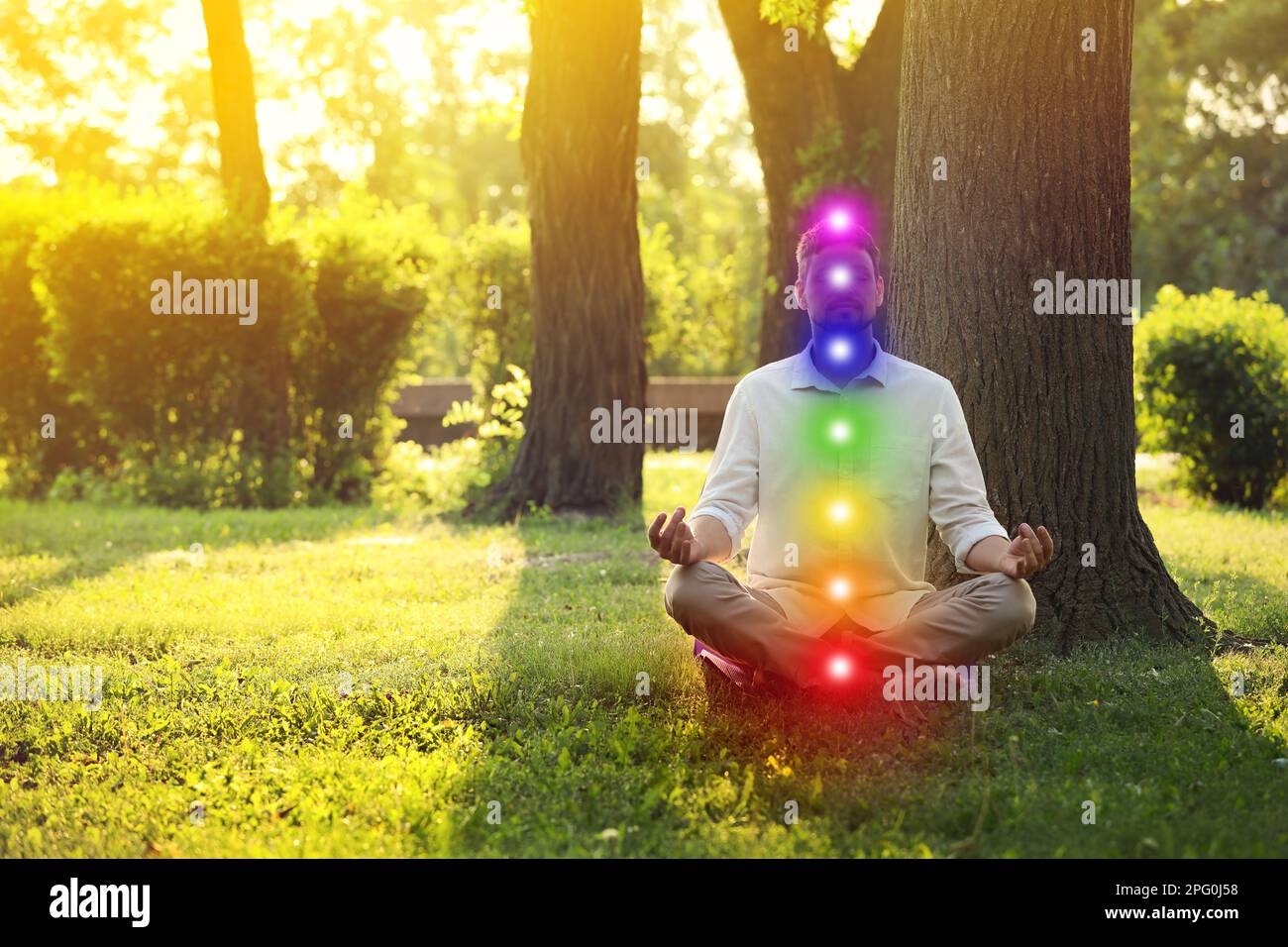 Homme méditant dans le parc le jour d'été ensoleillé. Schéma de sept chakras, illustration Banque D'Images