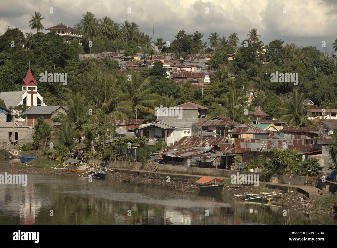 Des colonies, un bâtiment d'église et un paysage vallonné sont photographiés en premier plan de la rivière Tondano (rivière Manado) dans la zone côtière de la ville de Manado, au nord de Sulawesi, en Indonésie. Banque D'Images