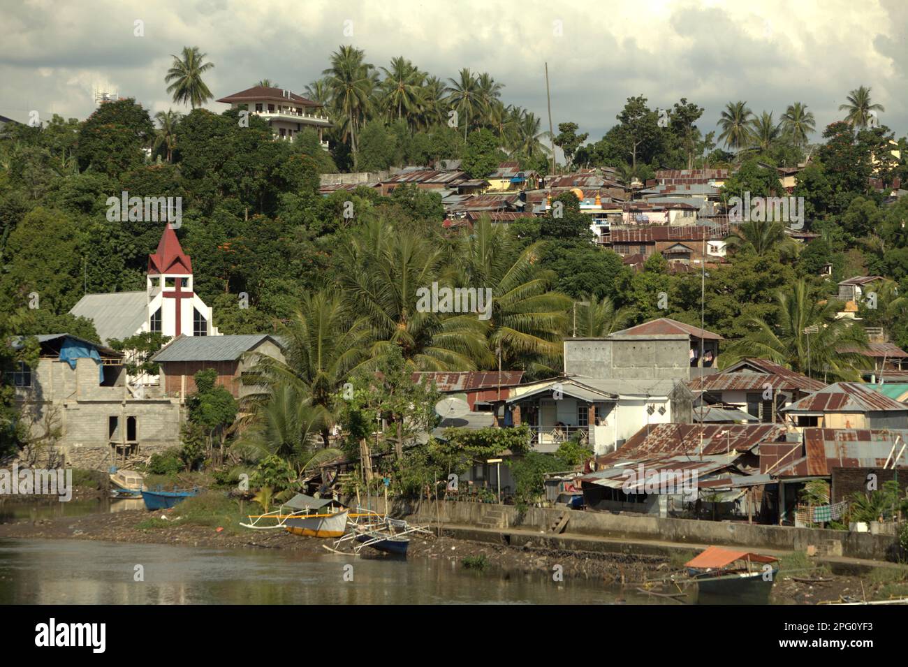 Des colonies, un bâtiment d'église et un paysage vallonné sont photographiés en premier plan de la rivière Tondano (rivière Manado) dans la zone côtière de la ville de Manado, au nord de Sulawesi, en Indonésie. Banque D'Images