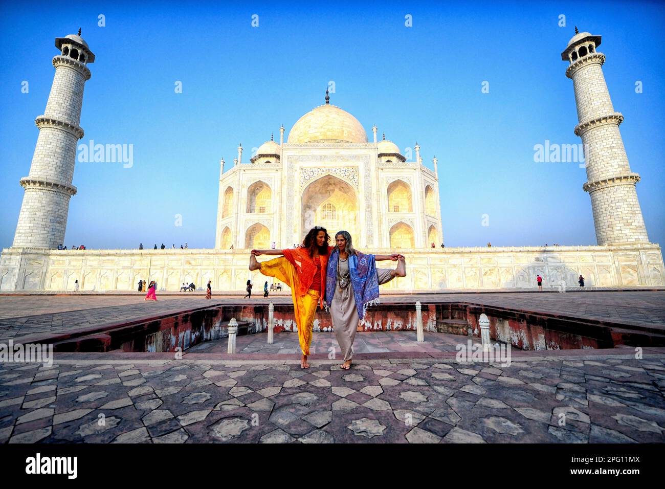 Les touristes étrangers vus posant dans différents styles de Yoga (exercice physique) devant le Taj Mahal à Agra. Le Taj Mahal est un mausolée situé sur la rive droite de la rivière Yamuna - Agra, Inde, construit par l'empereur Mughal Shah Jahan en mémoire de sa femme préférée, Mumtaz. Le Taj Mahal est considéré comme le meilleur exemple de l'architecture de Mughal, un style qui combine des éléments des styles architecturaux persan, Oman, indien et islamique. Le Taj Mahal figure sur la liste des sept merveilles modernes du monde et est également un site protégé du patrimoine mondial de l'UNESCO depuis 1983. Banque D'Images