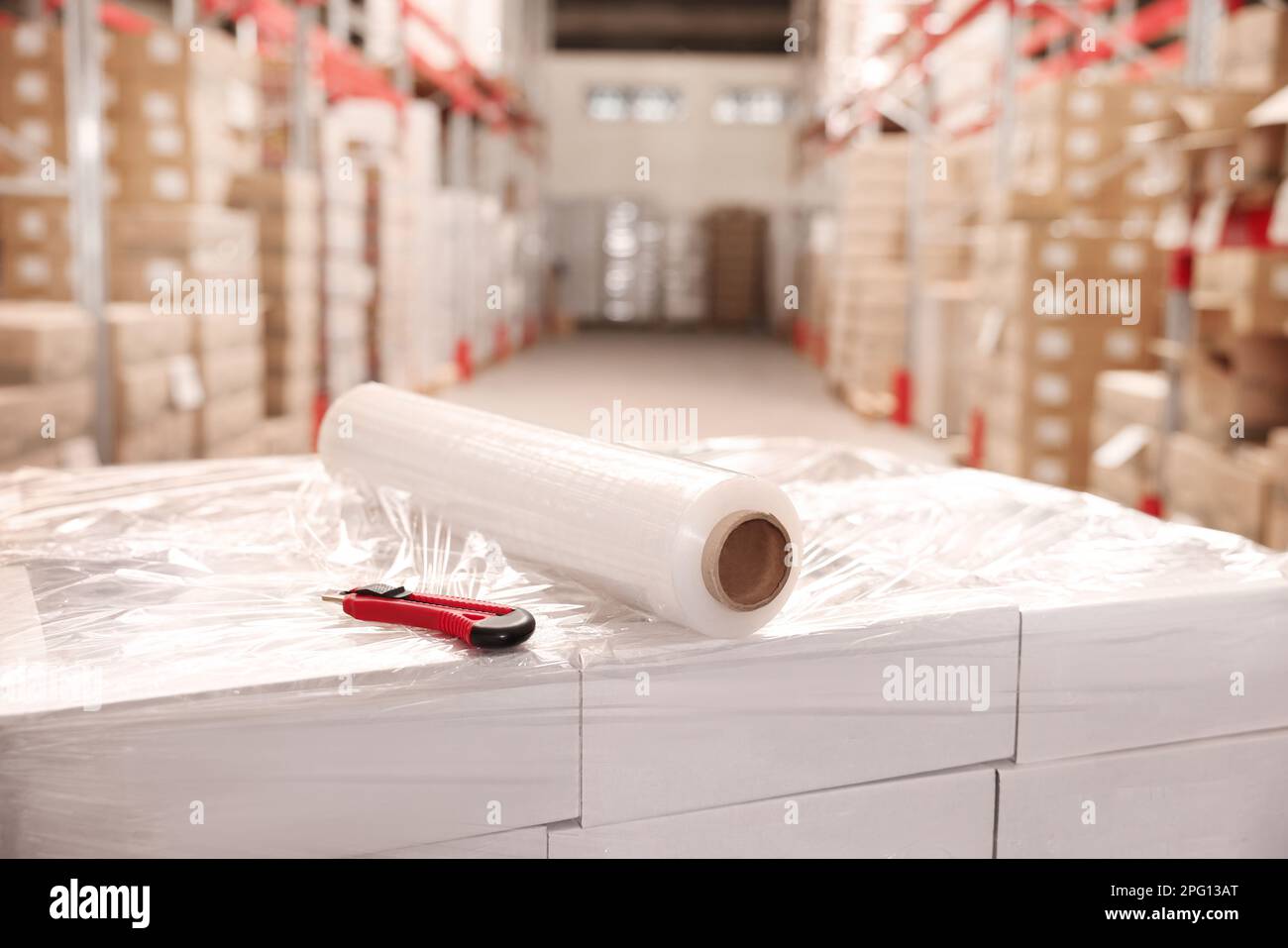 Rouleau de papier d'emballage extensible et couteau utilitaire sur les boîtes dans l'entrepôt Banque D'Images