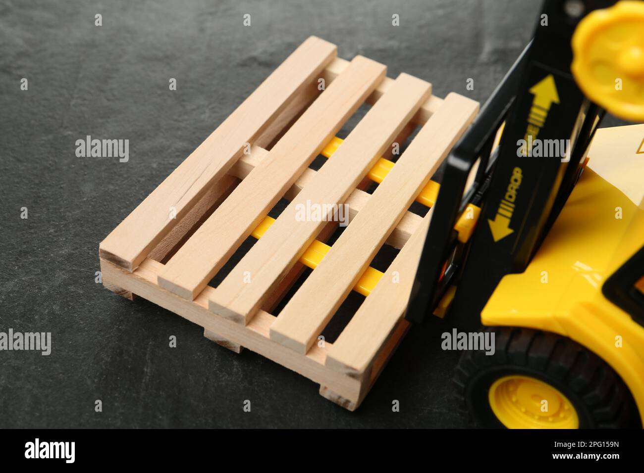 Chariot élévateur jouet avec palette en bois sur table noire, gros plan Banque D'Images