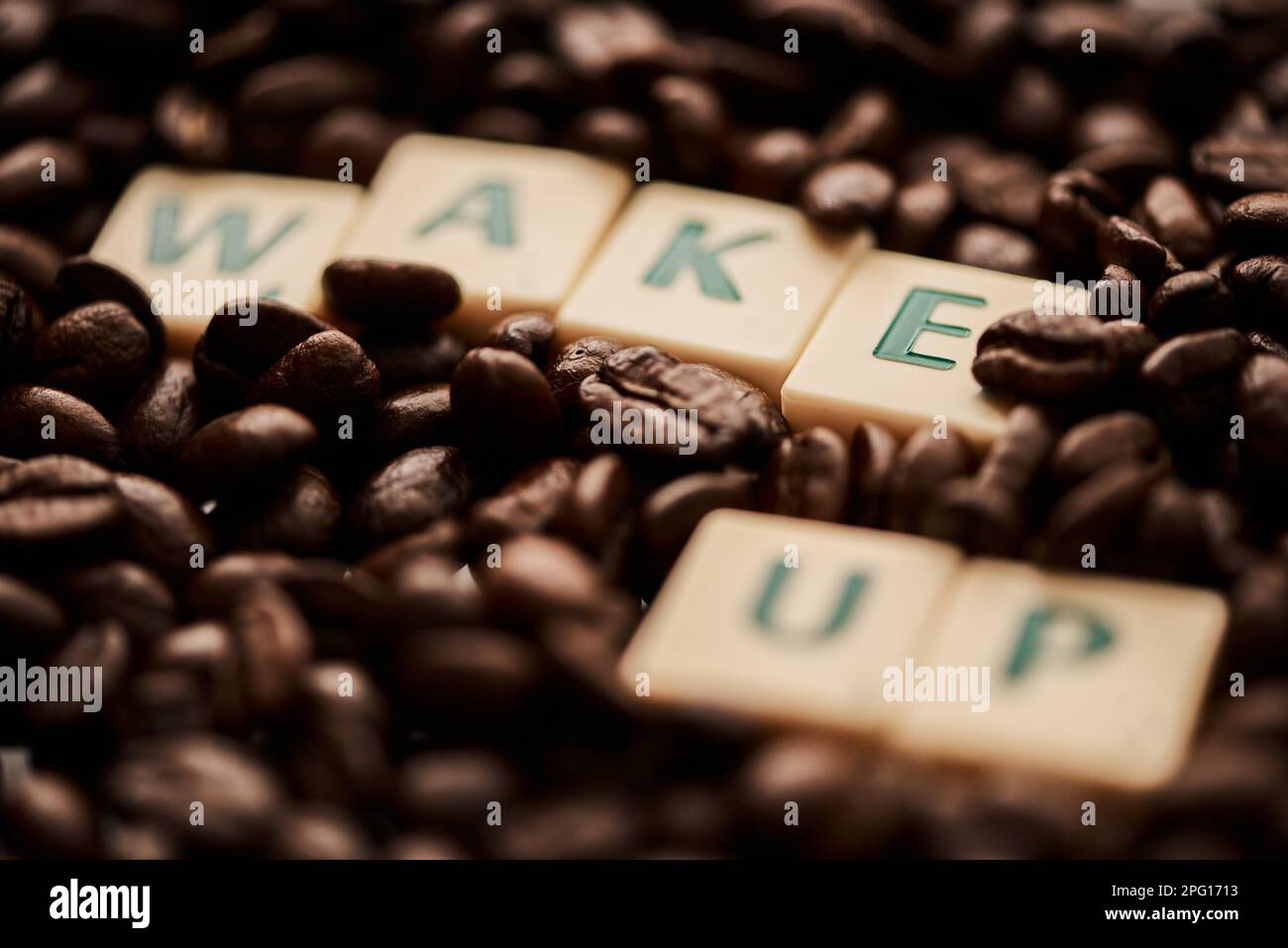 Réveillez-vous au son d'une journée bien remplie. Gros plan de lettres en bloc formant les mots se réveiller sur une pile de grains de café. Banque D'Images