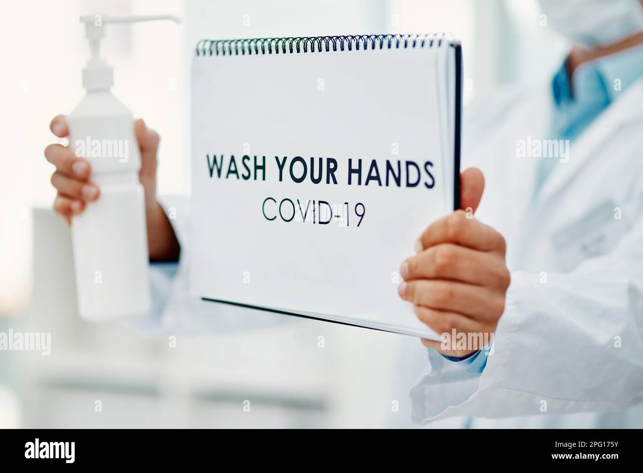 Il s'agit d'un poste de désinfection des mains. un scientifique tenant une affiche avec se laver les mains dessus et désinfectant pour les mains dans un laboratoire. Banque D'Images