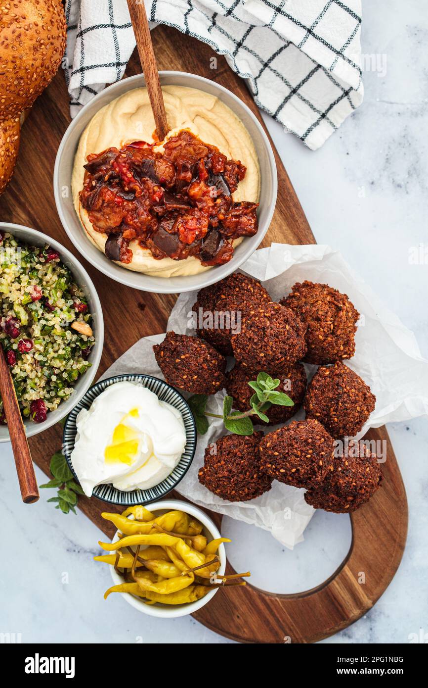 Table traditionnelle Shabbat : pain de challah, falafel, salade de quinoa, houmous sur une planche de bois. Concept alimentaire israélien. Banque D'Images