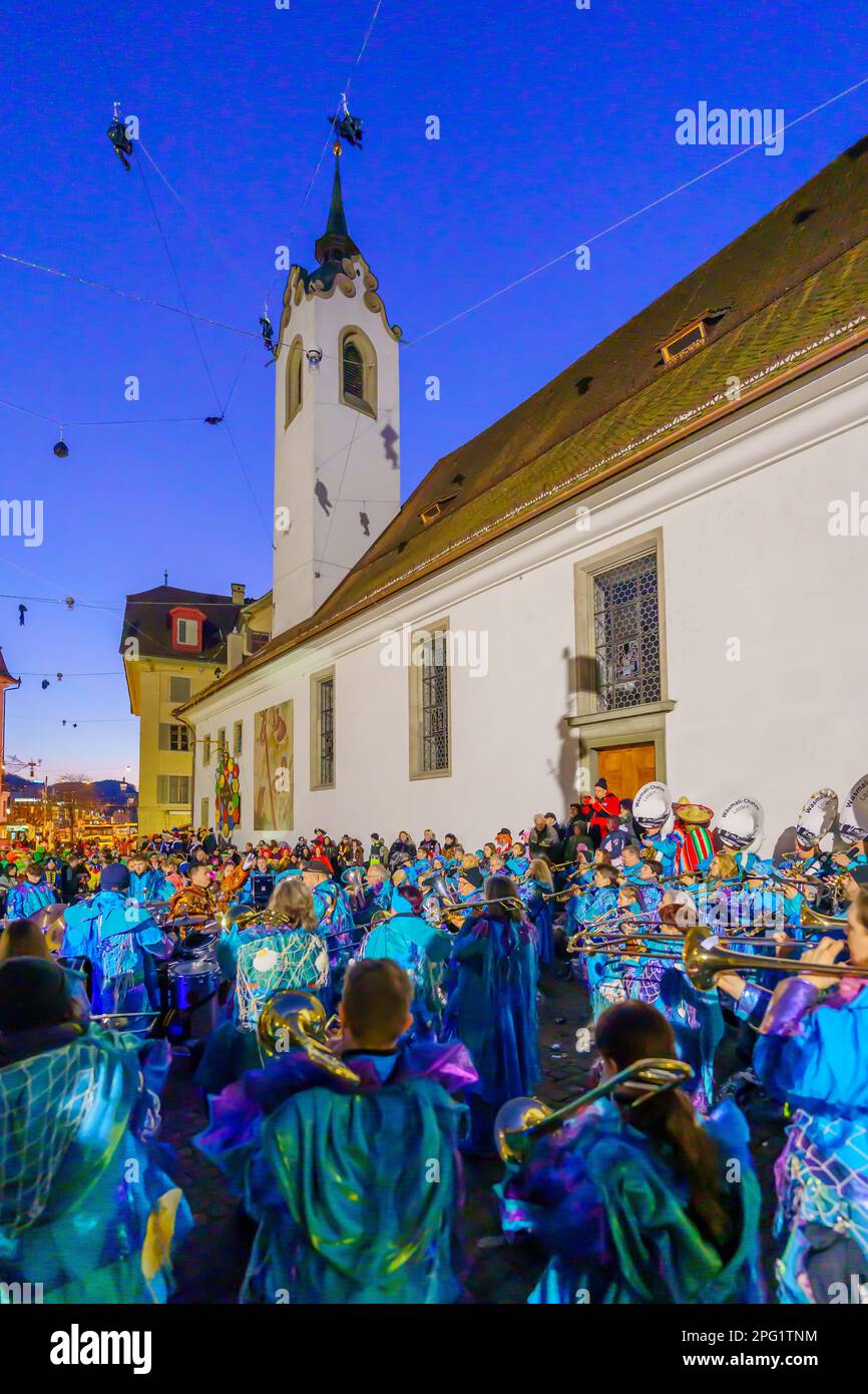 Lucerne, Suisse - 20 février 2023: Groupe de musiciens en costumes et en foule, près de la rue Chapelle Pierre, au lever du soleil, partie du Fasnacht Carniva Banque D'Images