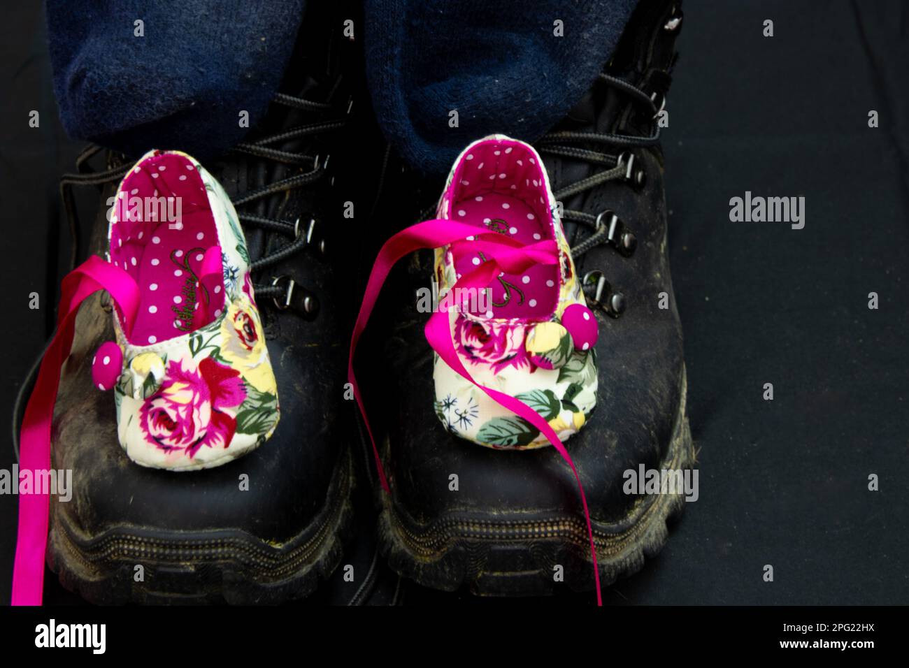 Bottes de marche pour adultes et chaussures pour bébés filles sur fond noir Banque D'Images