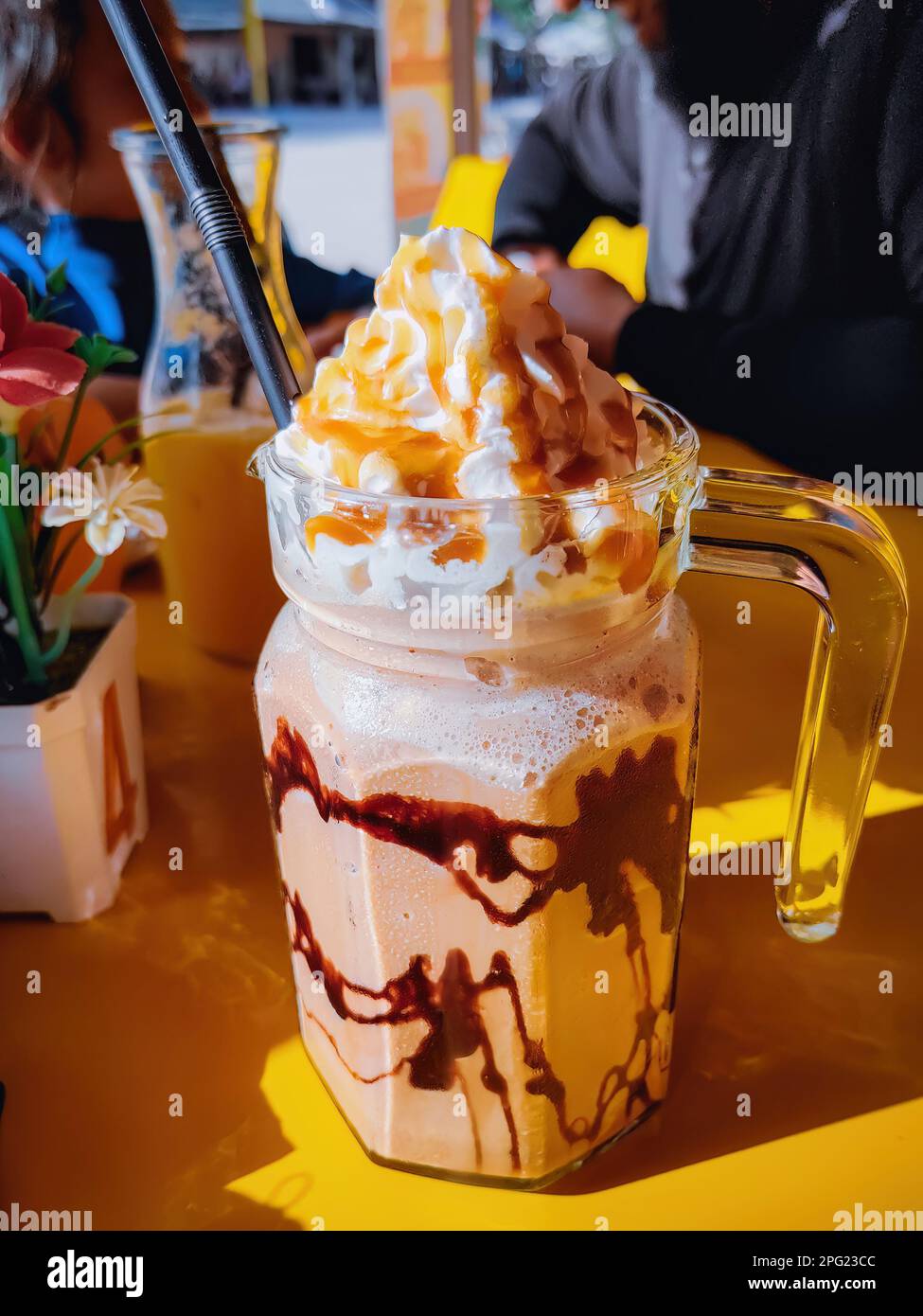 Frappuccino dans une grande tasse de verre sur la table au café par temps ensoleillé. Banque D'Images