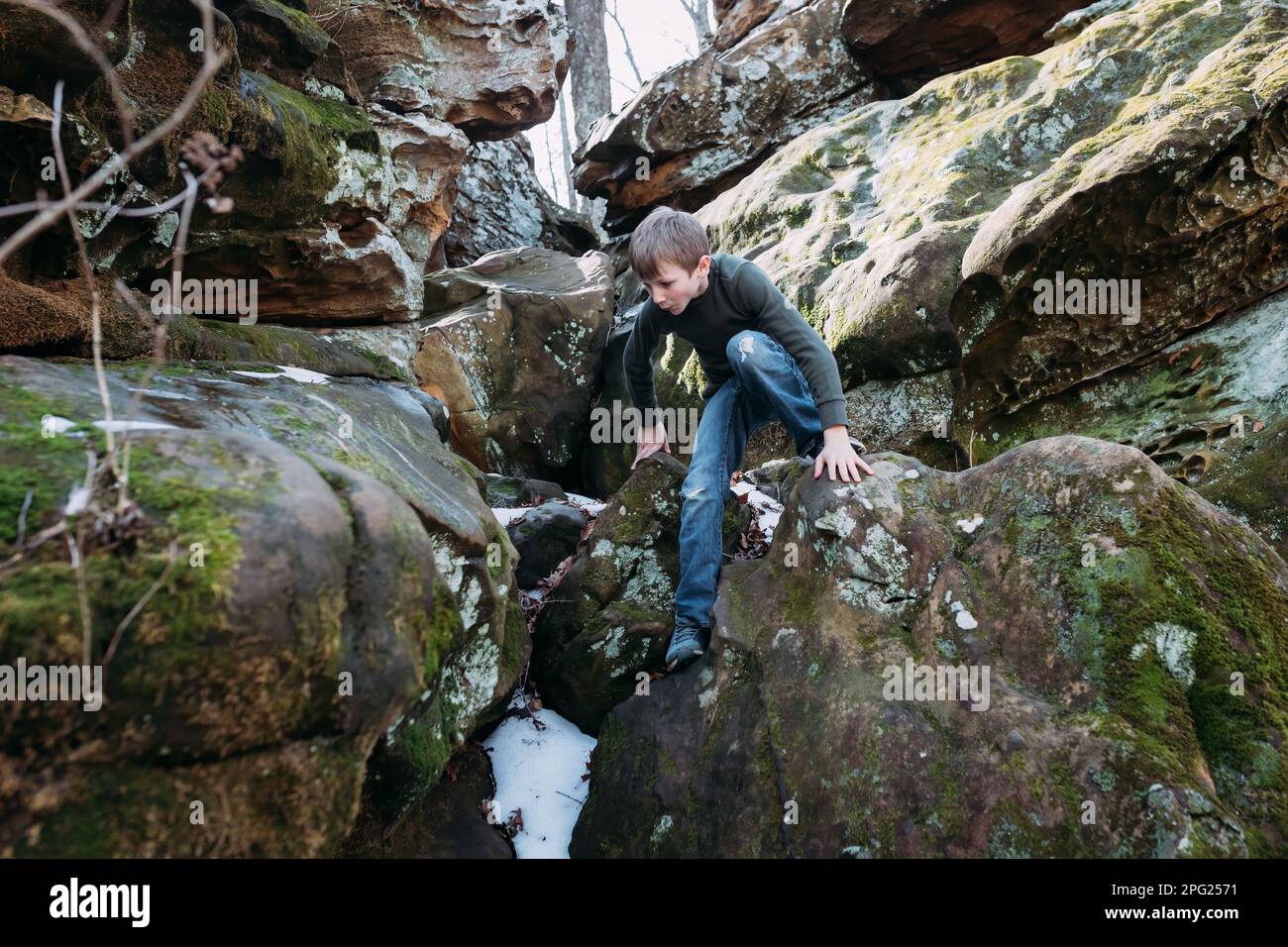 Un garçon se brouille sur les rochers lors d'une randonnée en forêt Banque D'Images