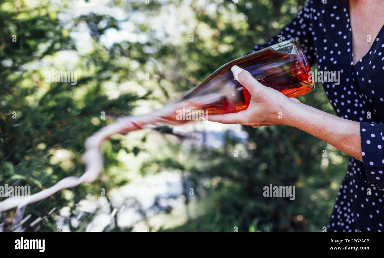 Une jeune femme ouvre une bouteille de vin mousseux au couteau. Sabrage. Gros plan. Banque D'Images