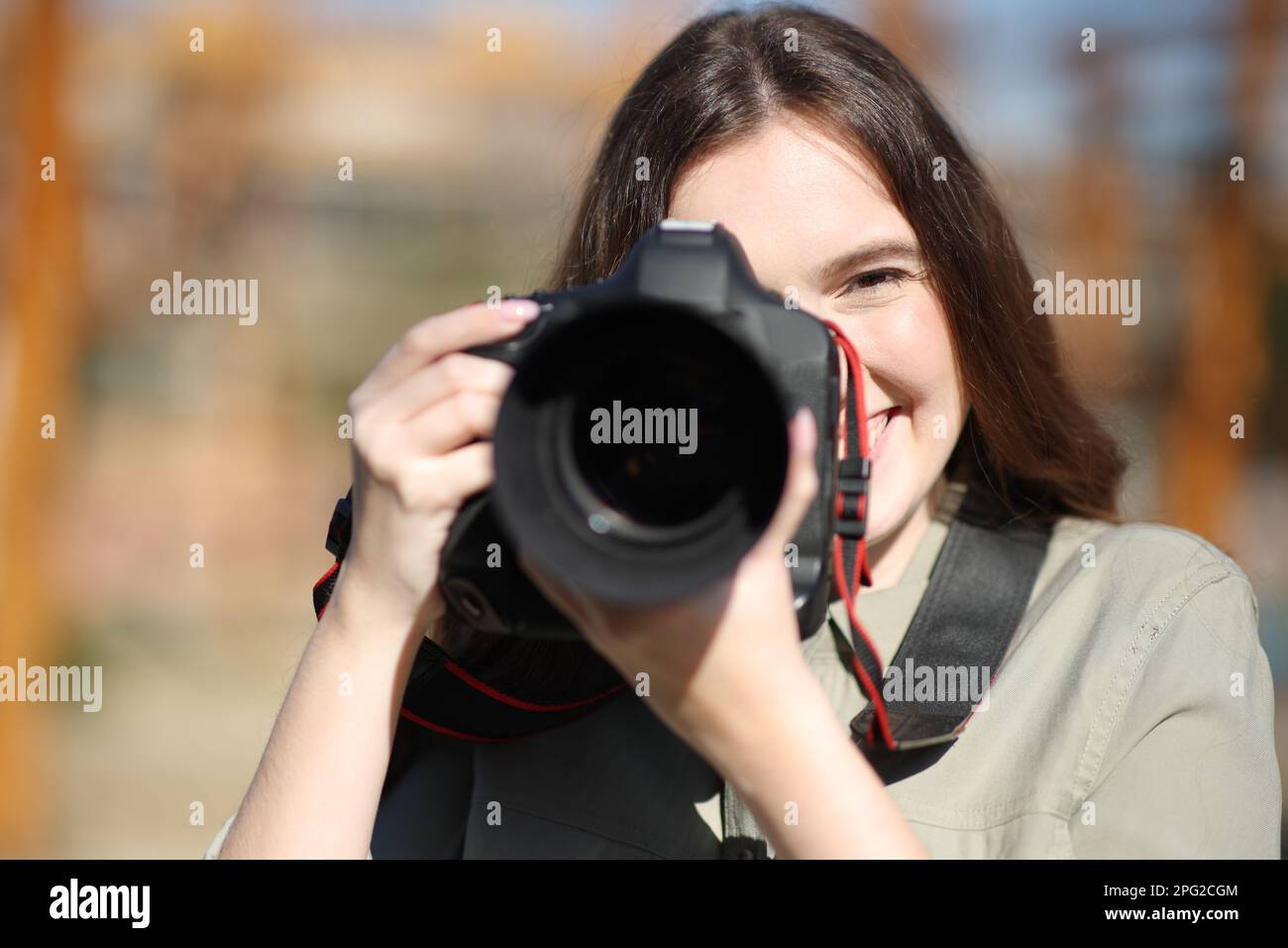 Portrait en vue avant d'un photographe heureux prenant des photos avec un appareil photo professionnel reflex numérique Banque D'Images